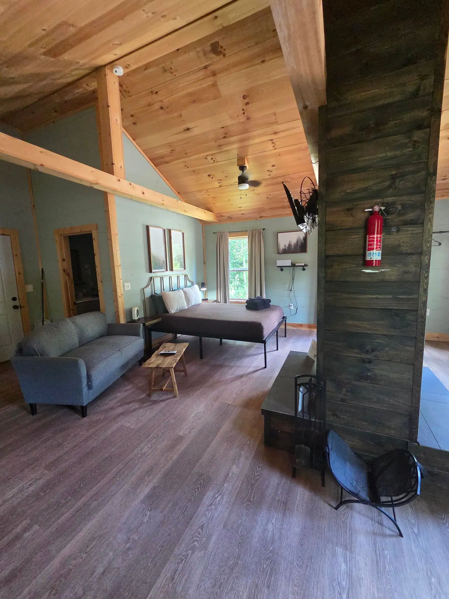 Vaulted interior with sofa, queen bed and fireplace column at Firefly's Landing