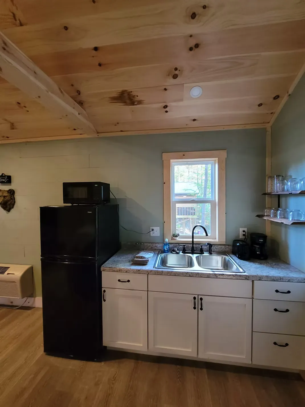 Kitchenette with floating wood shelves, wine glasses, and coffee maker at Firefly cabin