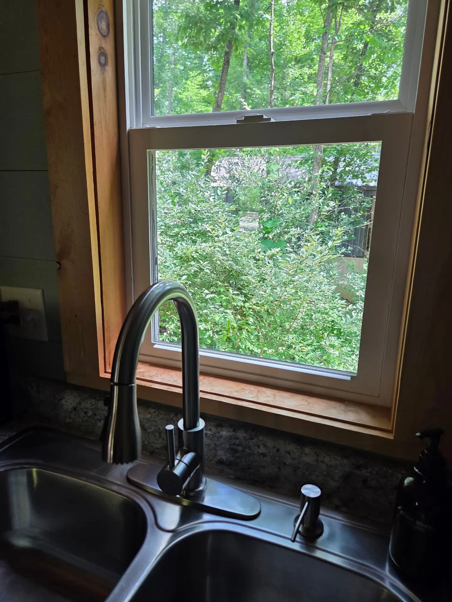 Kitchenette sink below a window looking into the woods at Firefly's Landing