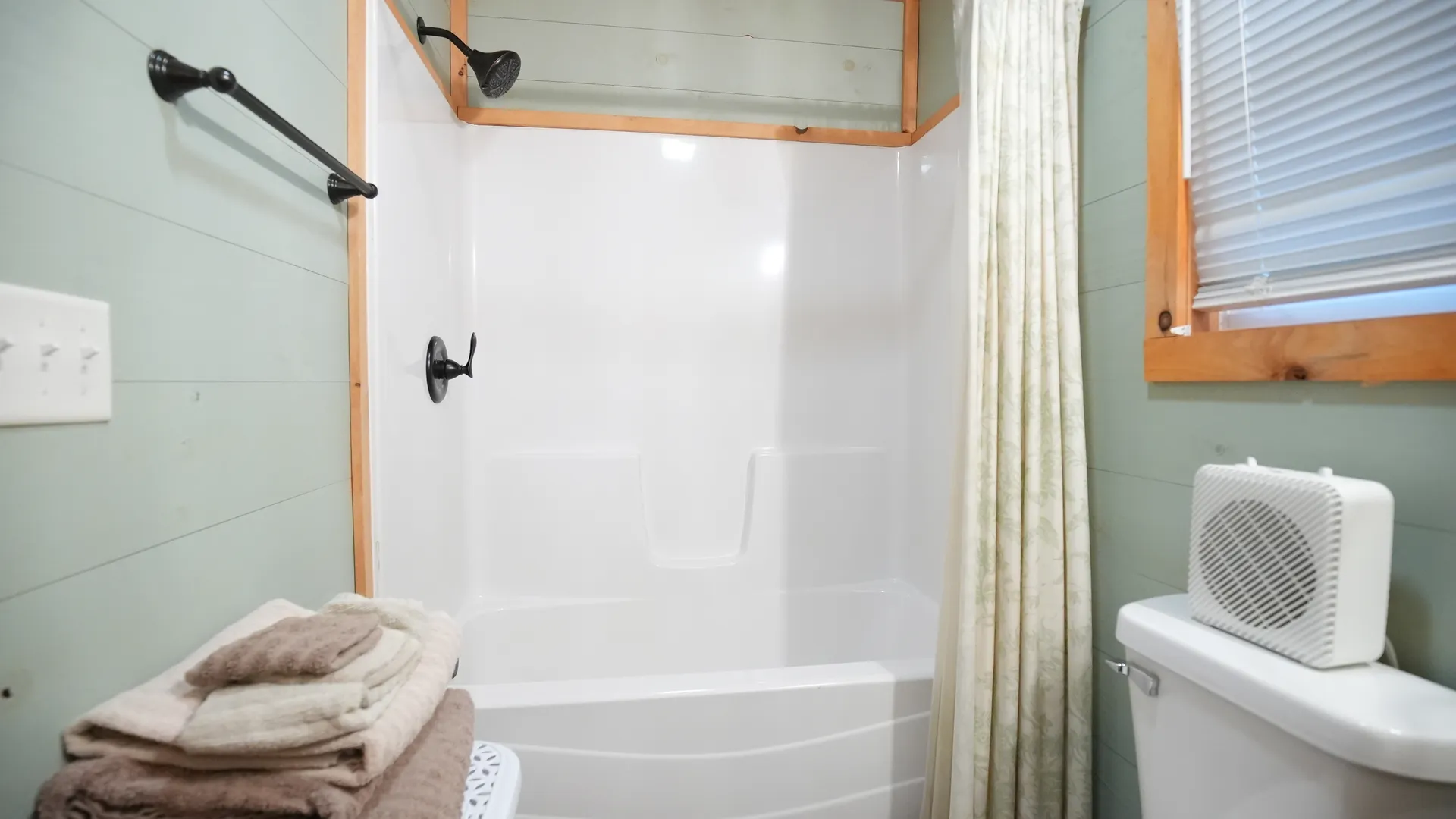 Bathtub and shower with curtain, folded towels, and window at Forest Aisle cabin