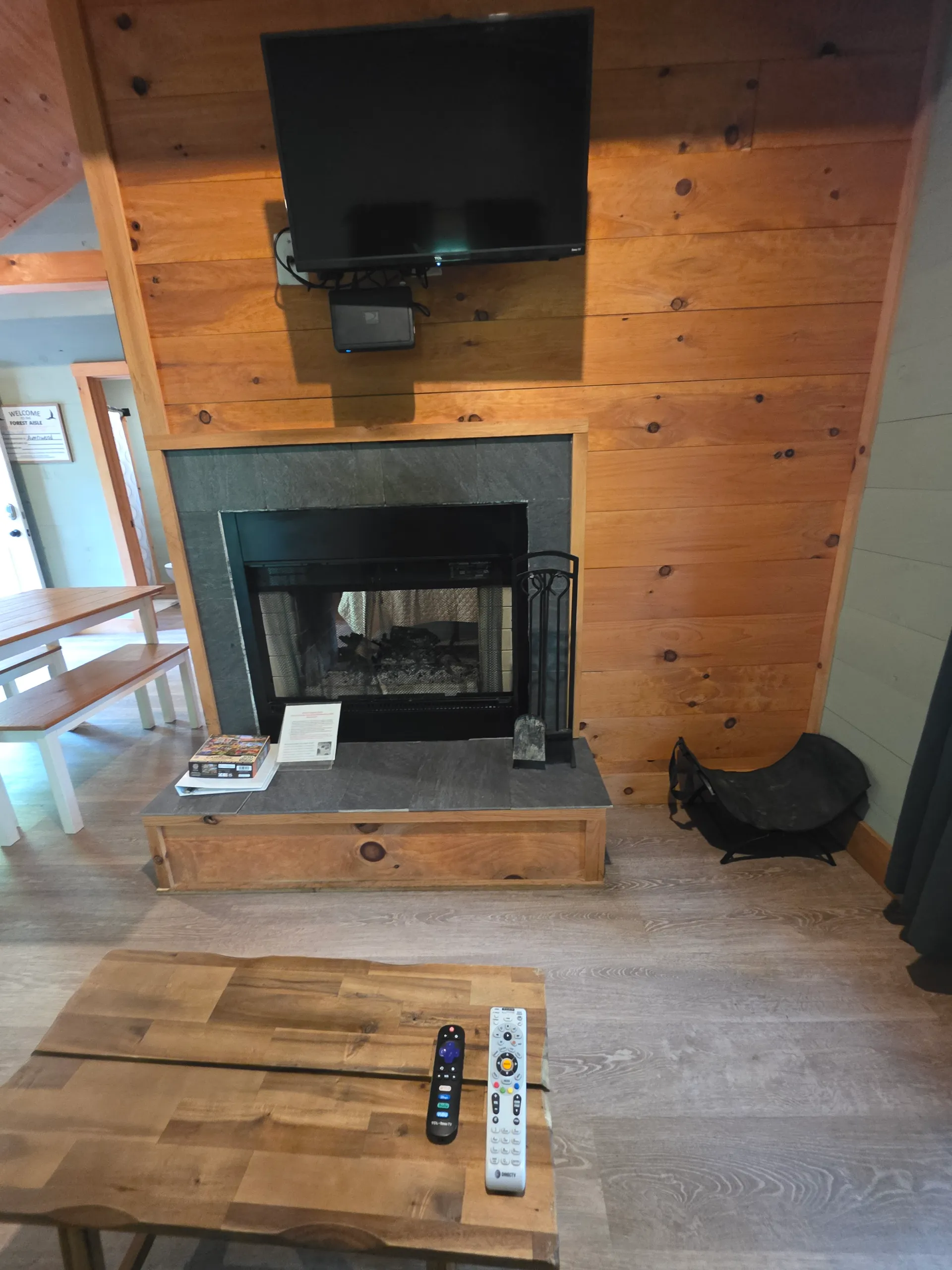 Fireplace close-up with TV, fire tools, and wood mantel at Forest Aisle cabin