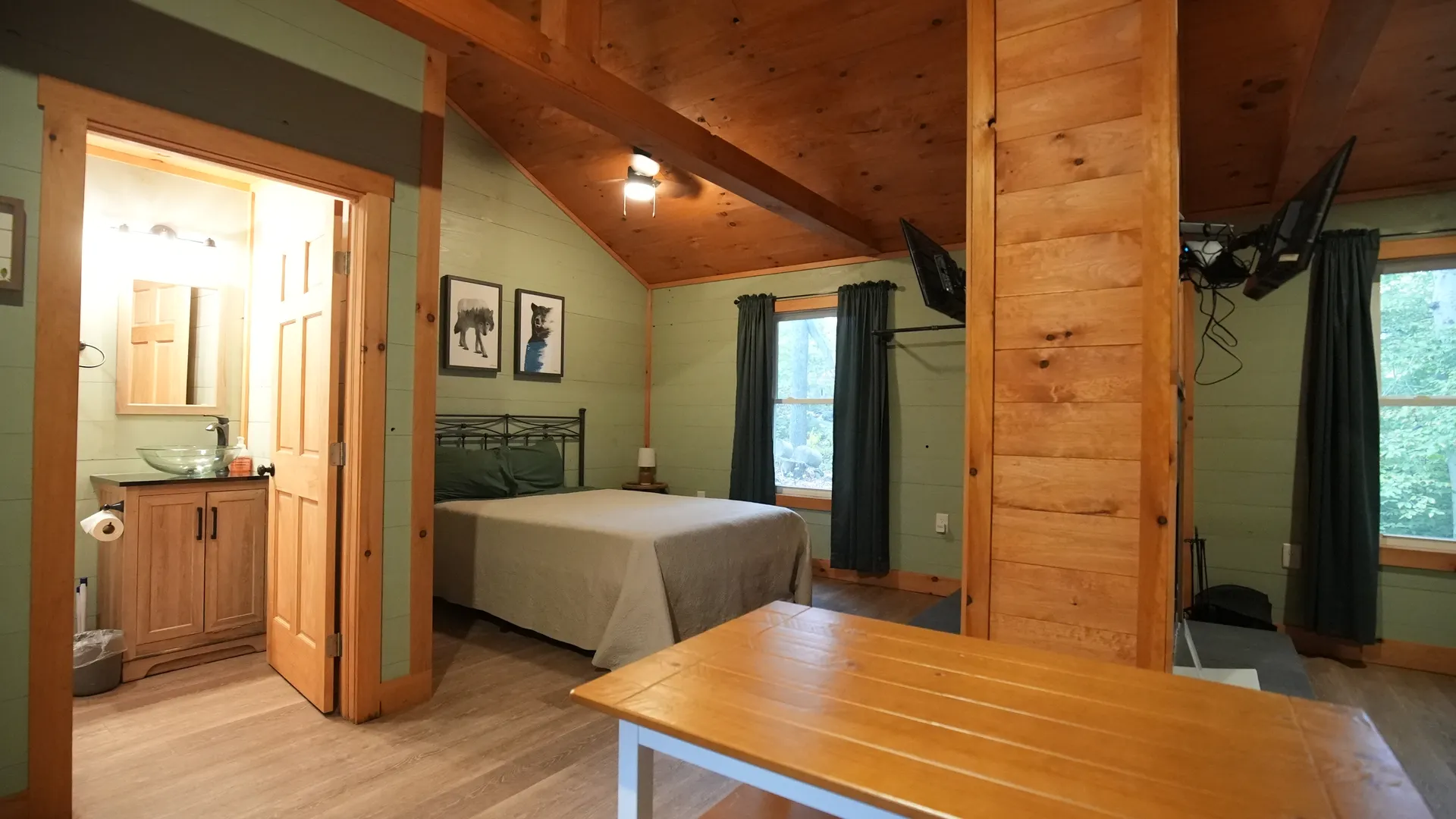 Interior showing the bedroom with queen bed, bathroom doorway, and dining table at Forest Aisle cabin