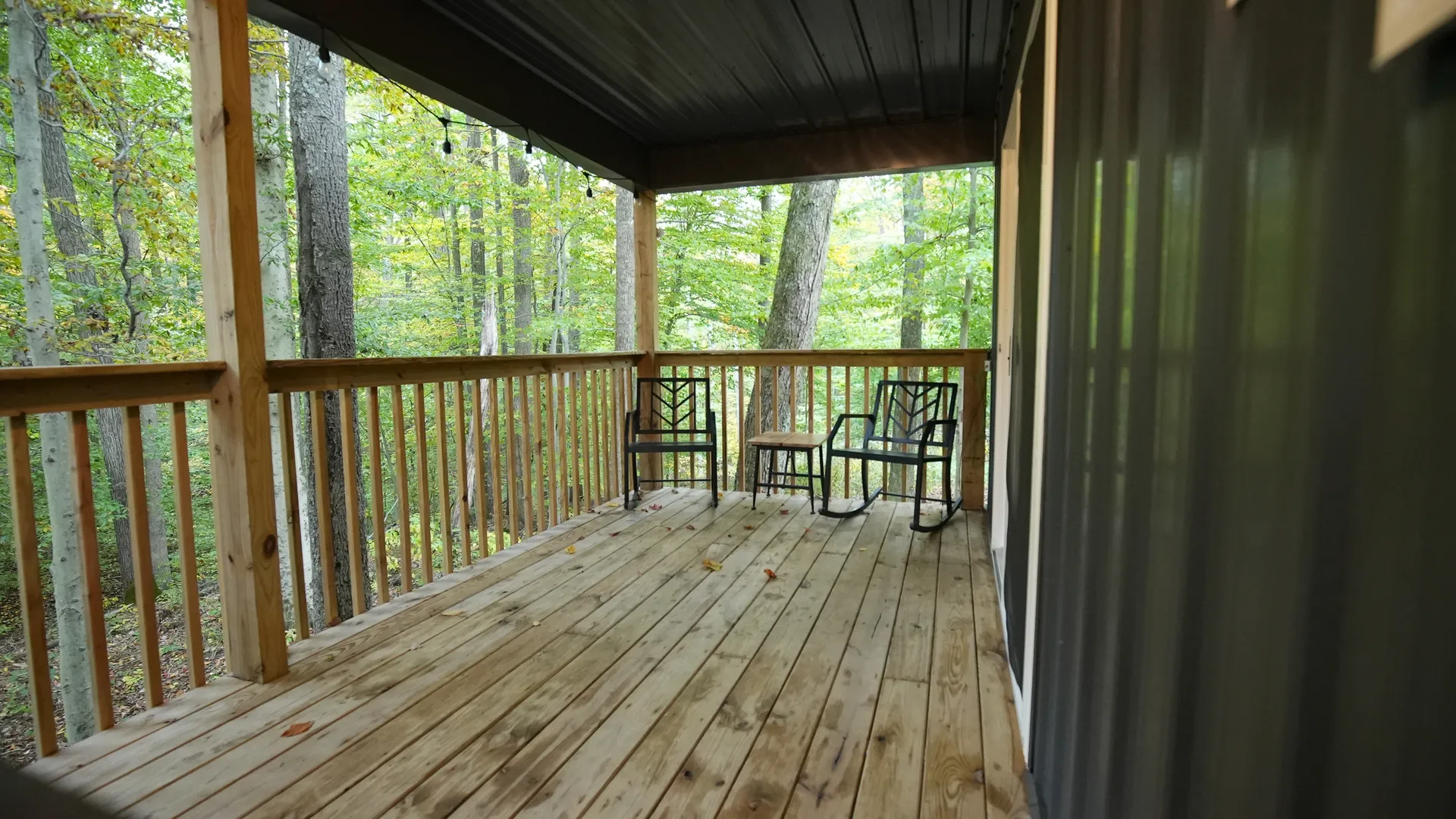 Front porch with two metal chairs and forest view at Forest Aisle cabin