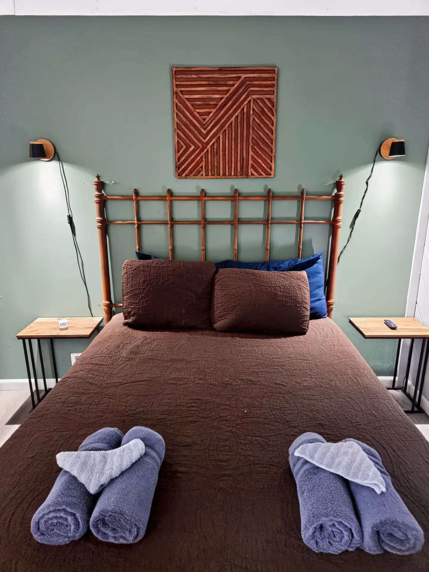 Queen bed with a wood headboard and reading lights in the first bedroom of The Getaway House.