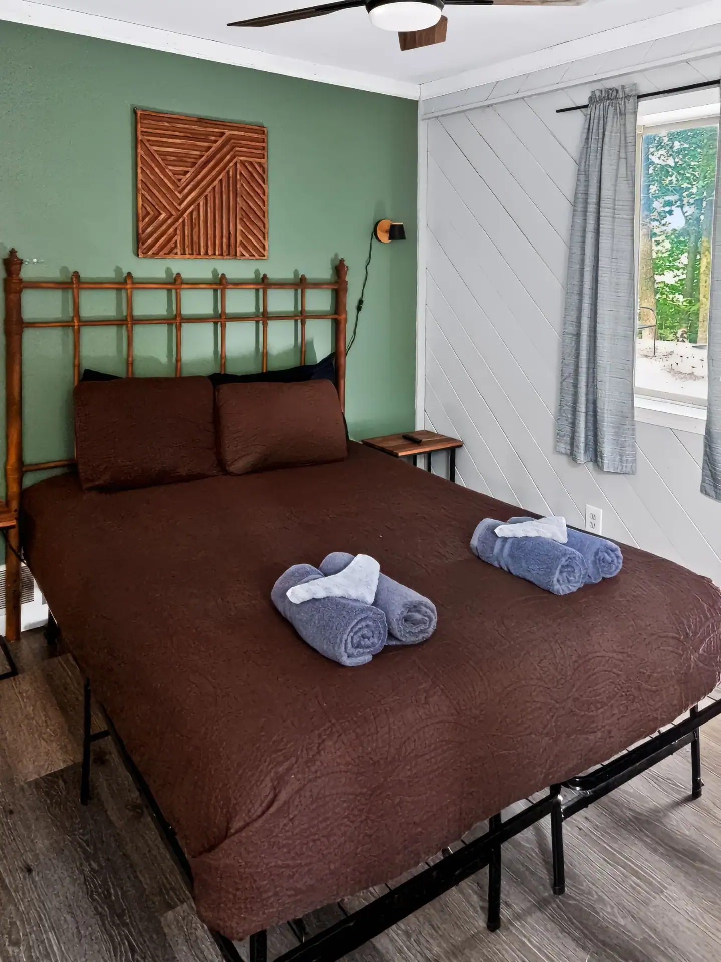First bedroom at The Getaway House with a queen bed, green accent wall and ceiling fan.