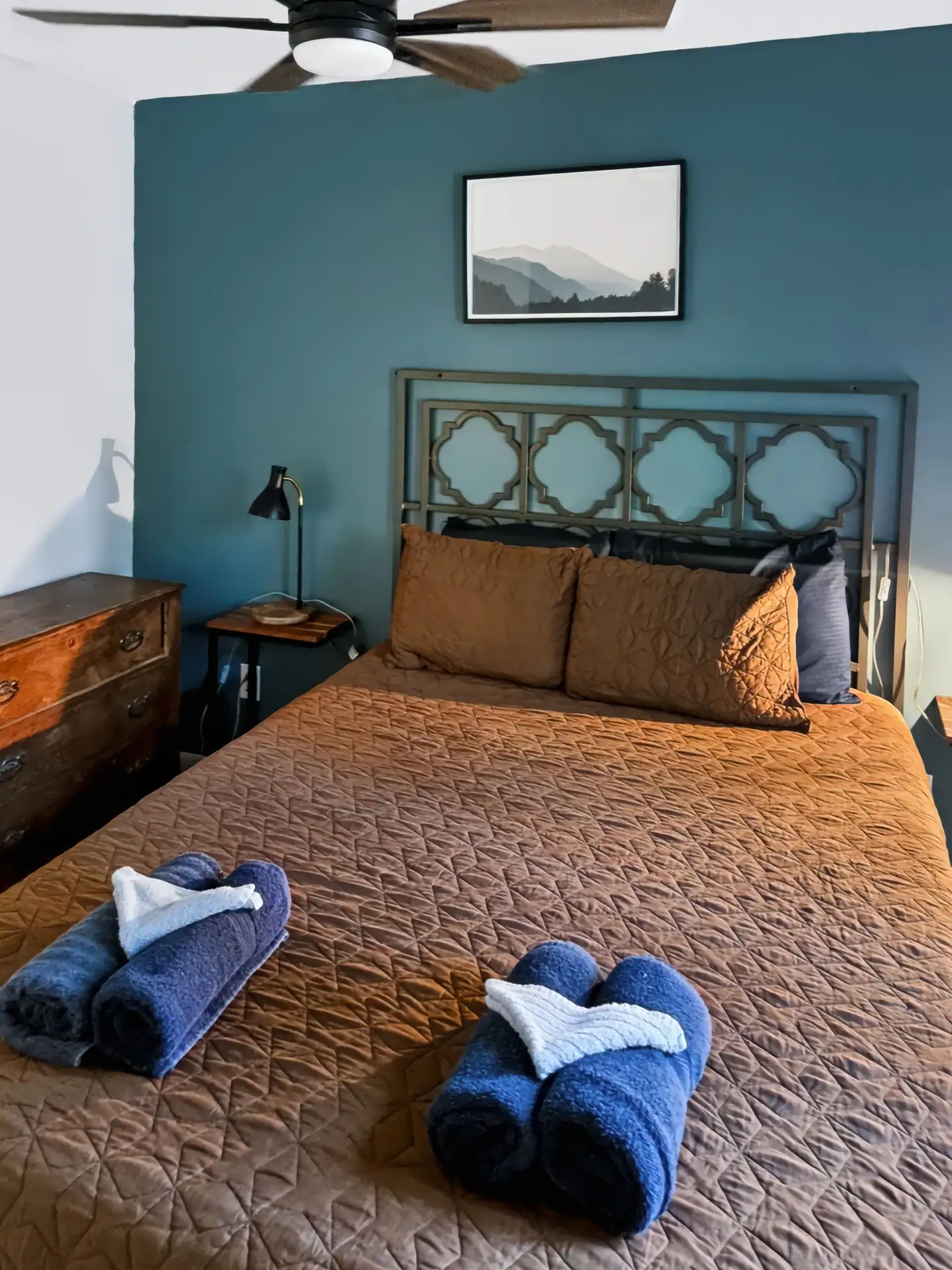 Second bedroom at The Getaway House with a queen bed, blue accent wall and ceiling fan.