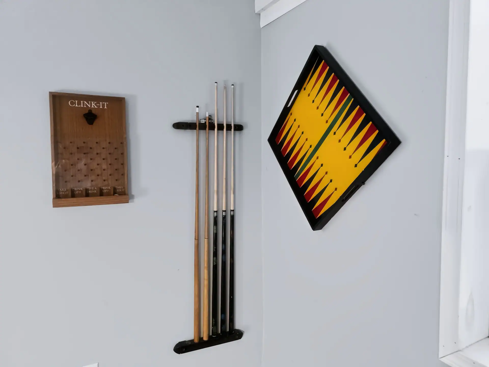 Pool cue rack and wall-mounted games in the game room of The Getaway House.