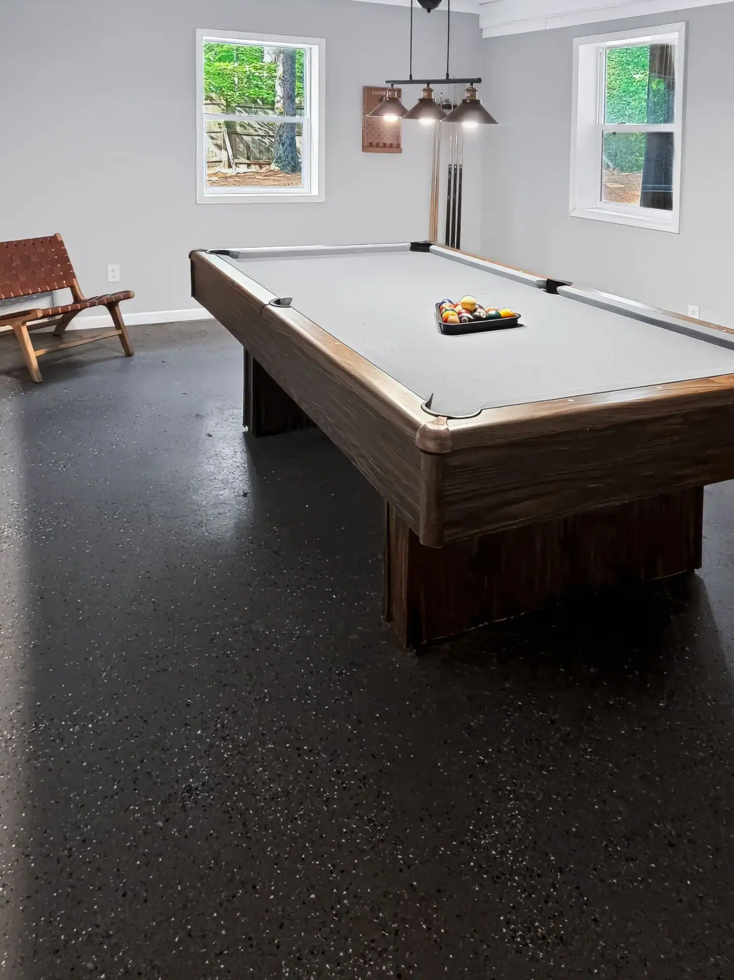 Pool table and leather sling chair in the bright game room of The Getaway House.