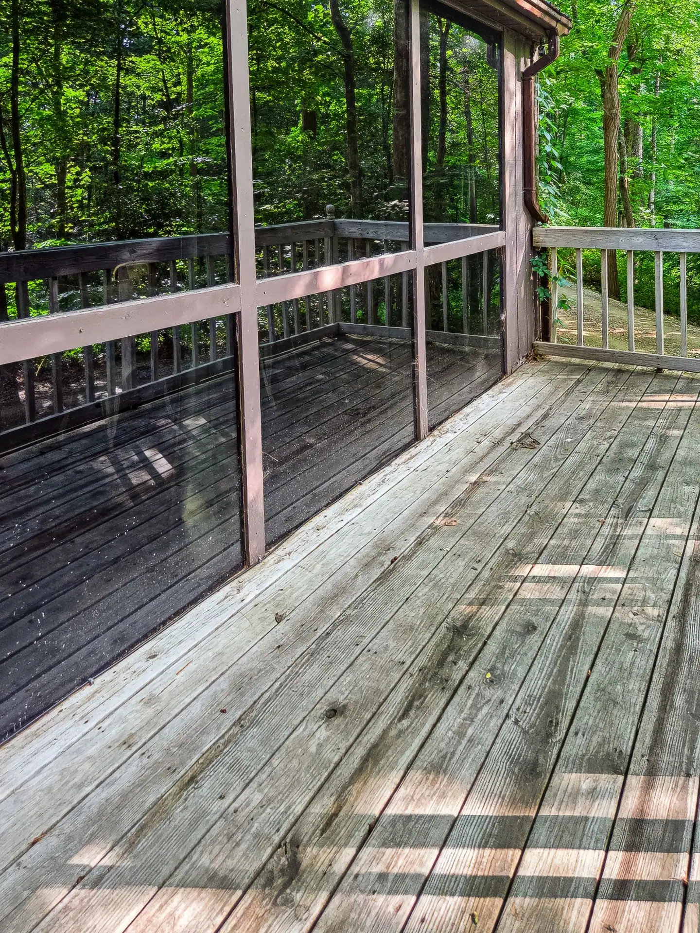 Covered wooden deck along the back of The Getaway House facing the woods.