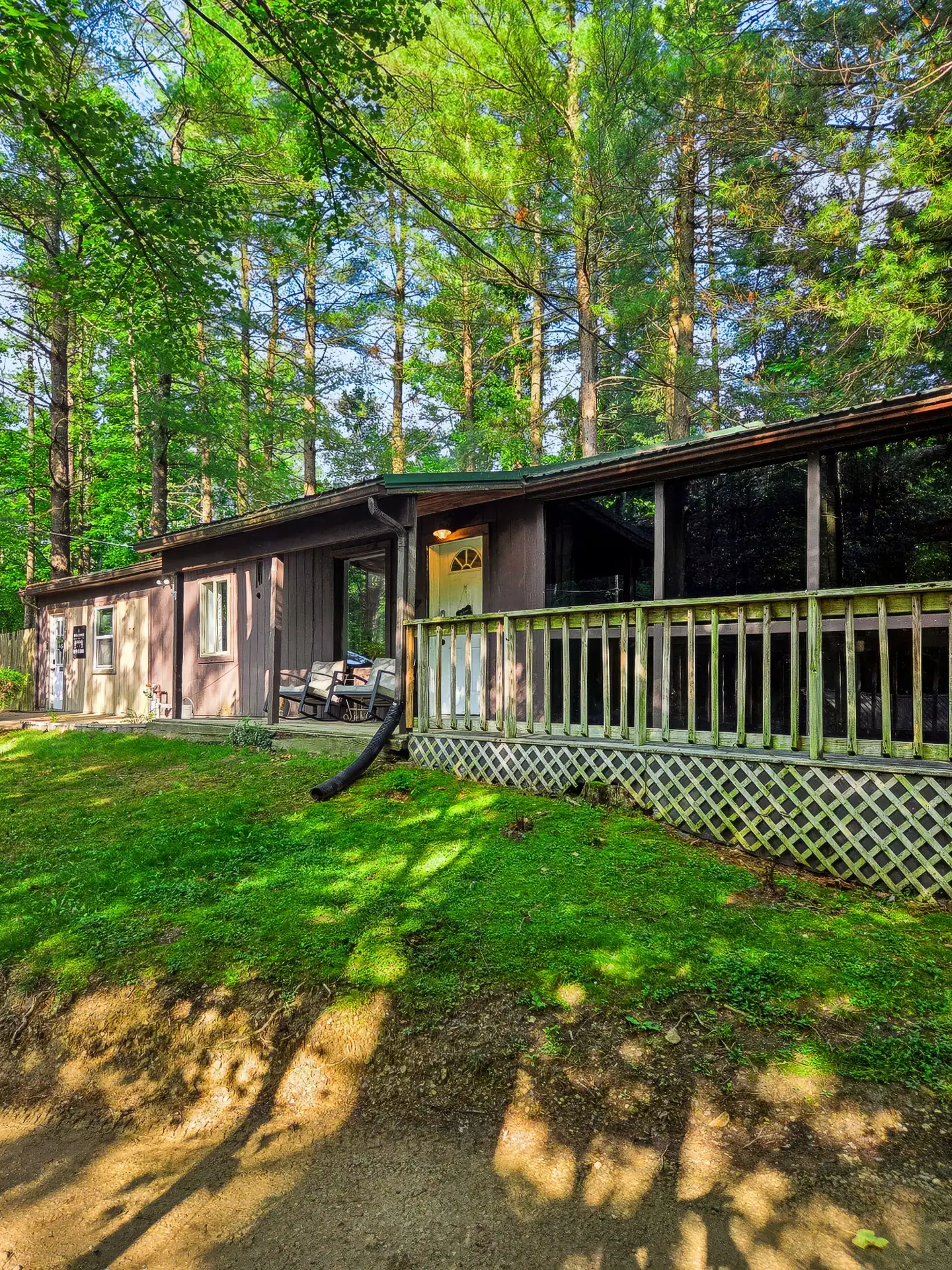 Side view of The Getaway House with its railed deck and lattice skirting in the woods.