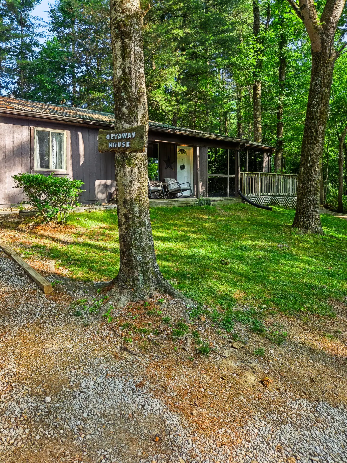 The Getaway House sign in front of the cabin with a green lawn and tall trees.