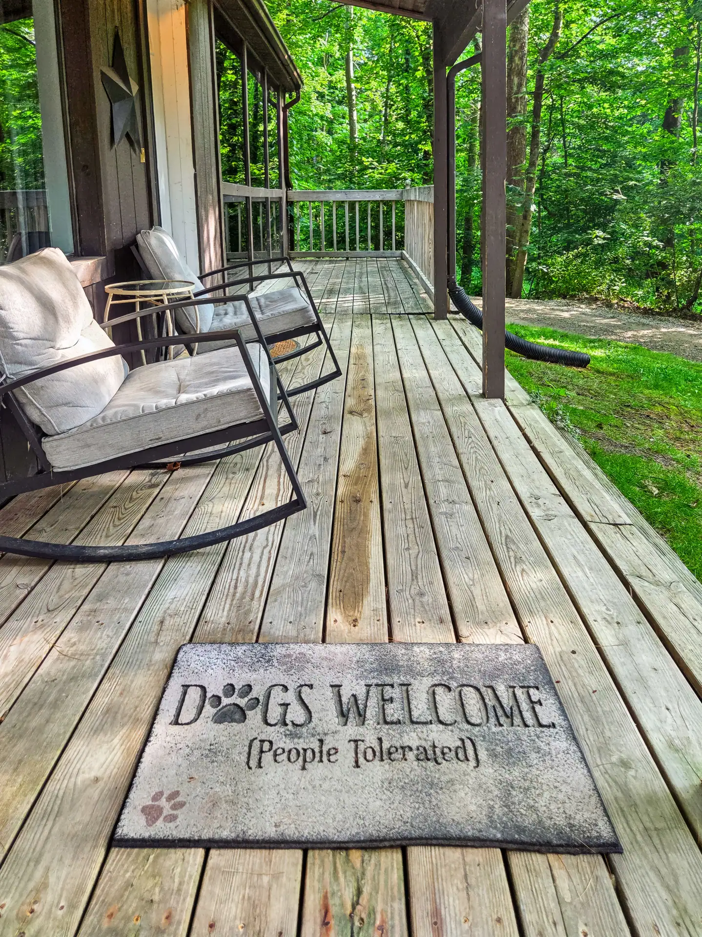 Covered front porch of The Getaway House with rocking chairs and a dog-friendly doormat.