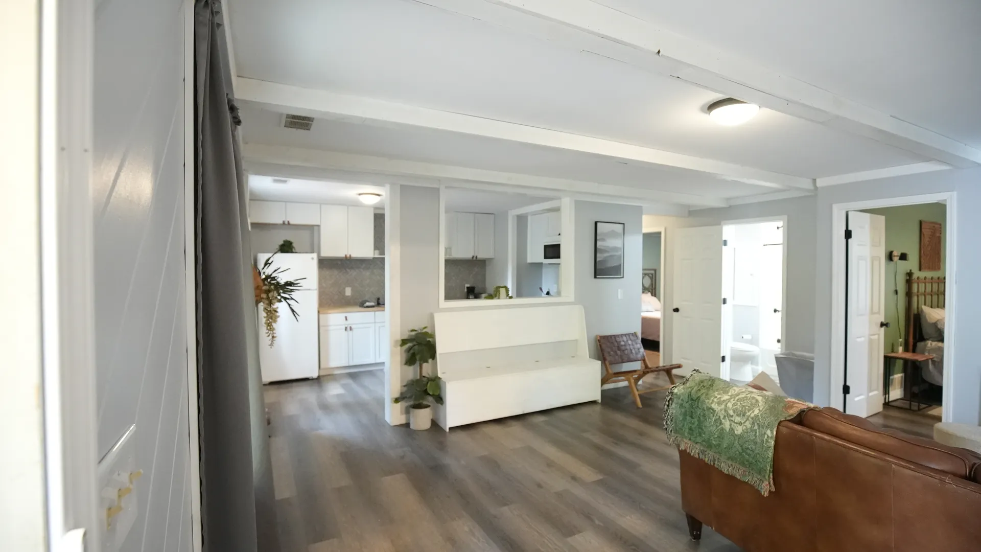 Open-concept living area with leather sofa, kitchen pass-through, and hardwood floors at Getaway House cabin
