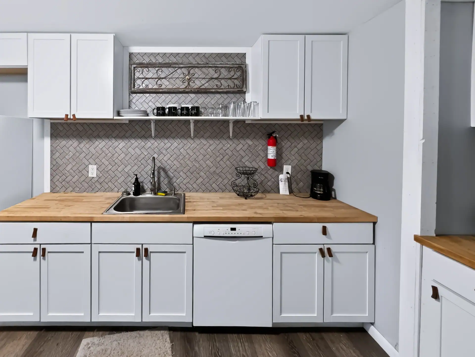 Full kitchen at The Getaway House with white cabinets, butcher block counters and a herringbone backsplash.