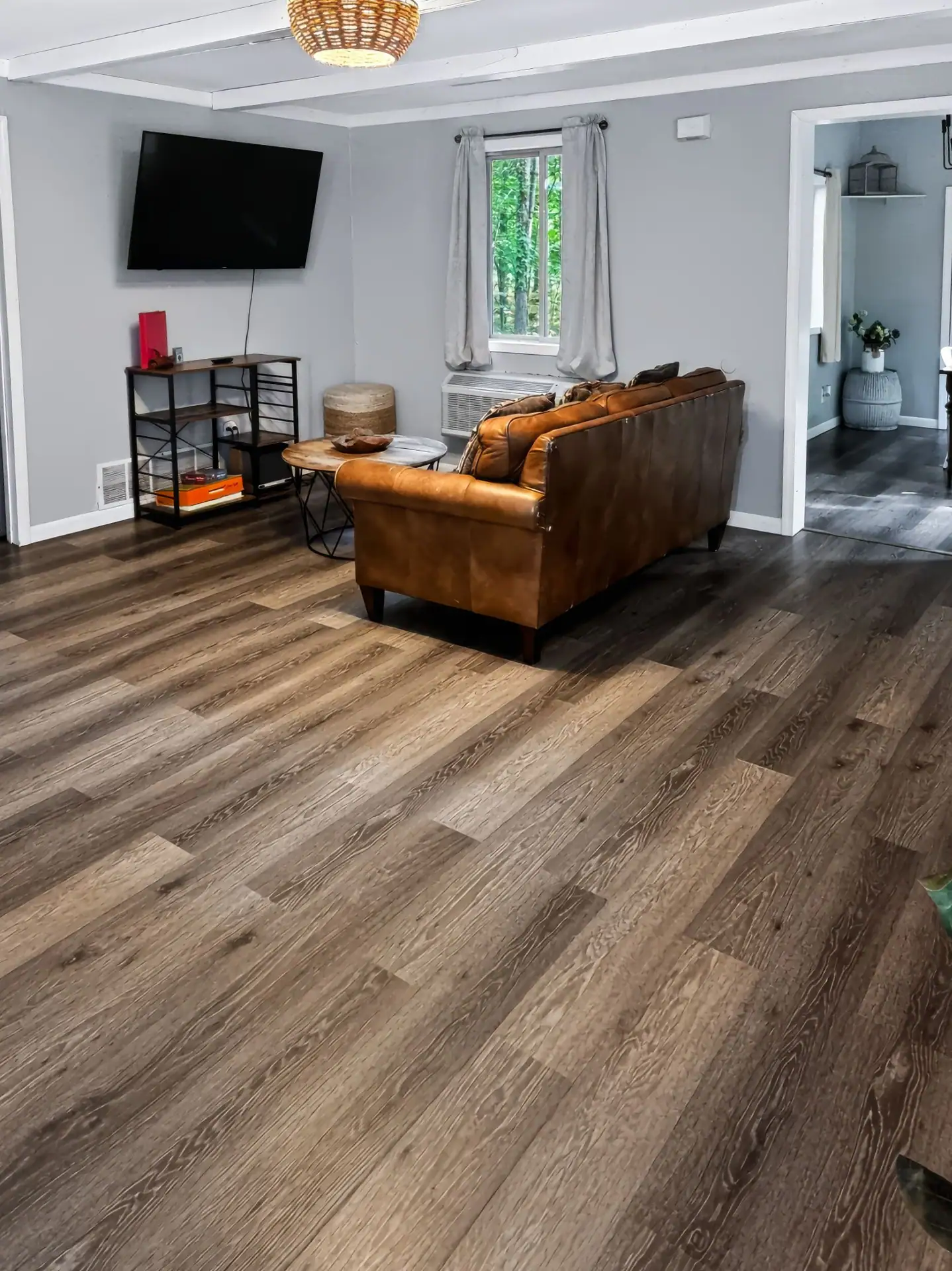 Open living room at The Getaway House with a leather sofa, wall-mounted TV and wood-look floors.