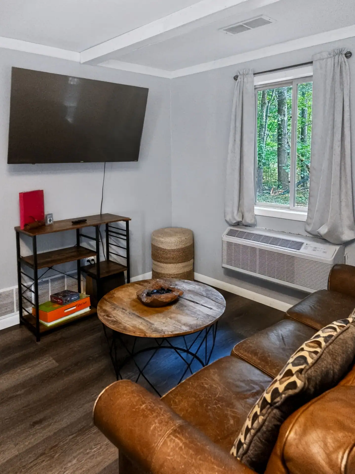Living room of The Getaway House with a wall-mounted TV and a window to the woods.