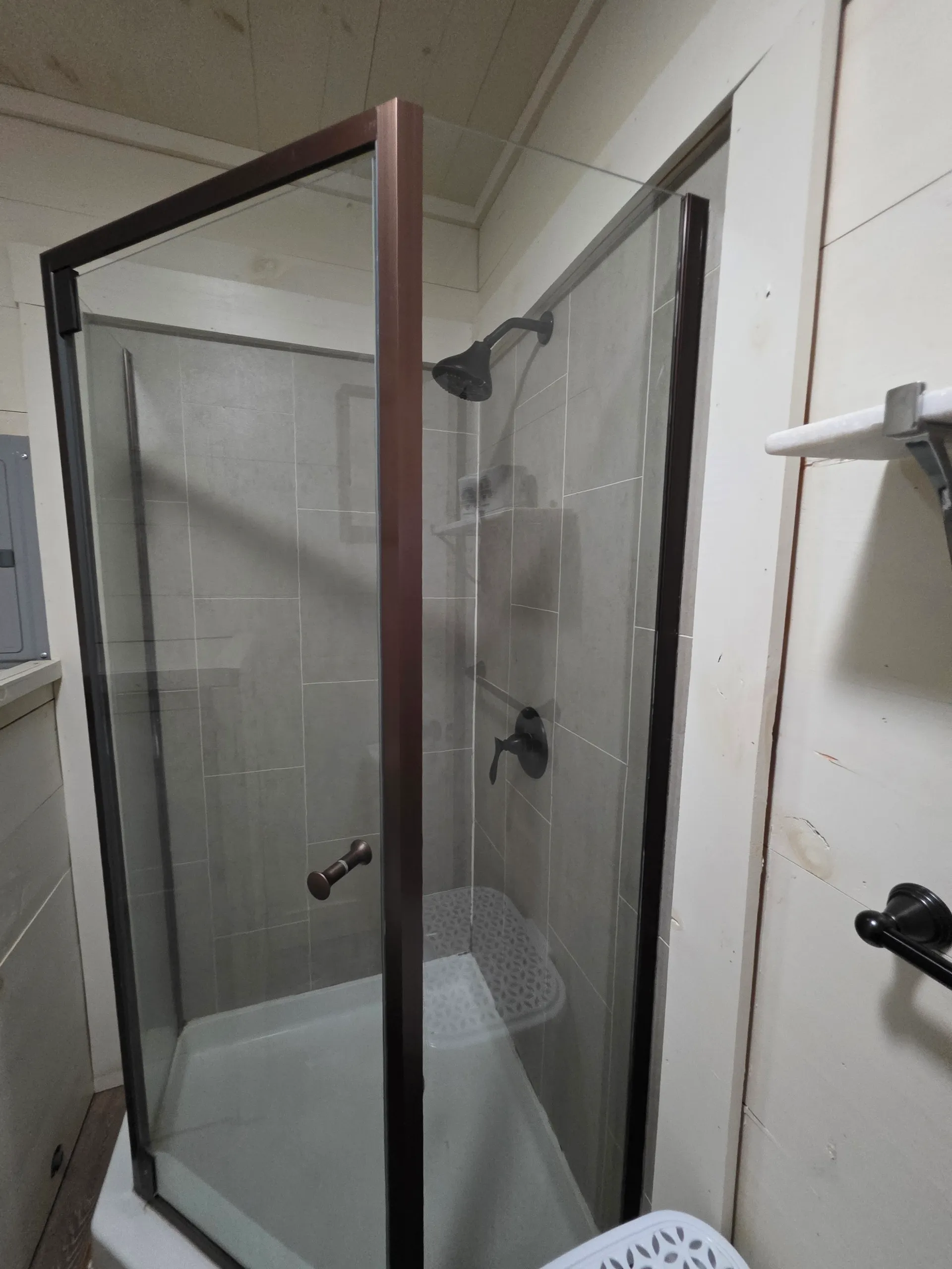 Glass-enclosed walk-in shower with gray tile and rainfall showerhead at Hummingbird cabin