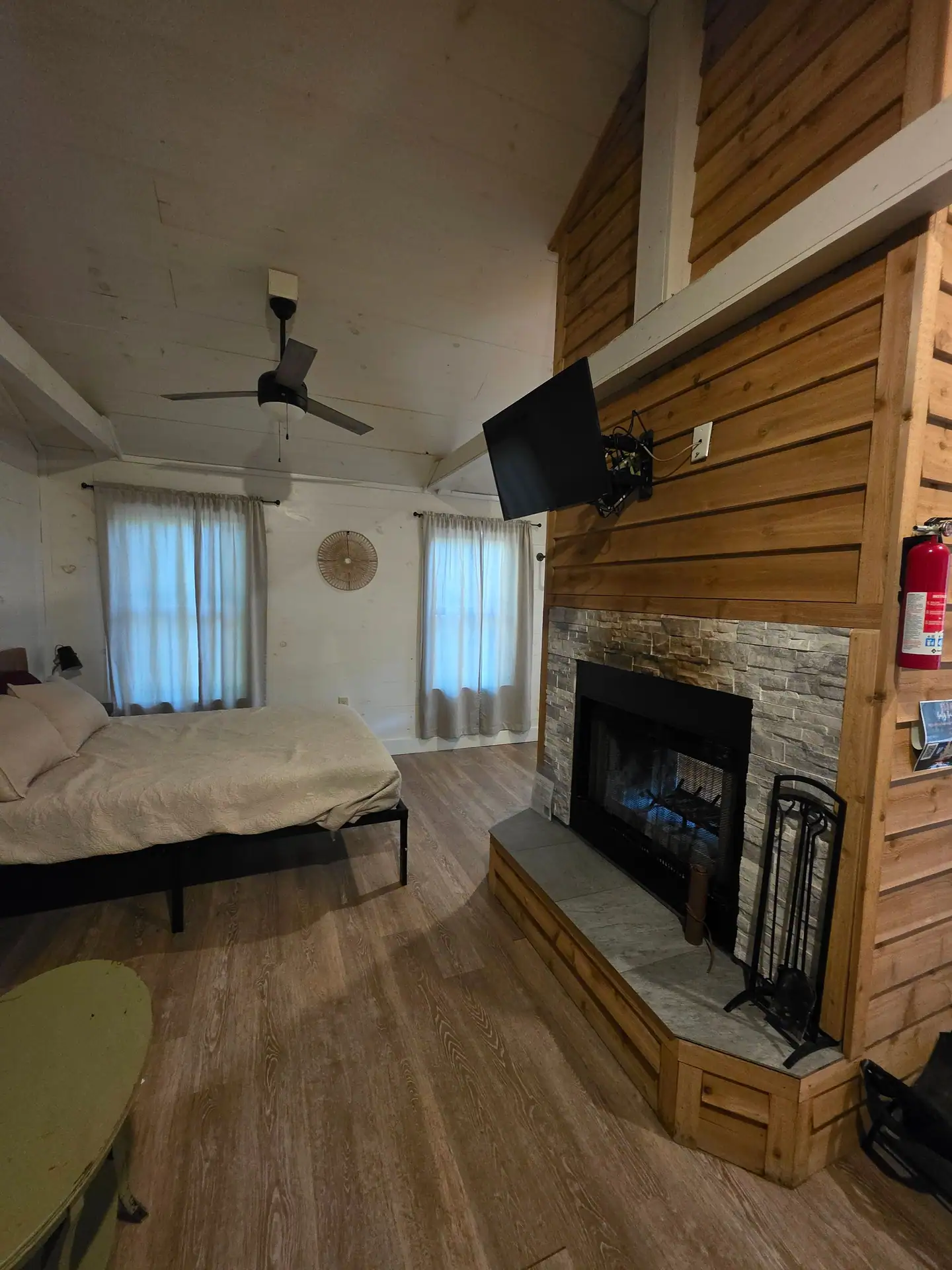 Queen bed beside the double-sided fireplace and mounted TV under the vaulted ceiling at Hummingbird cabin