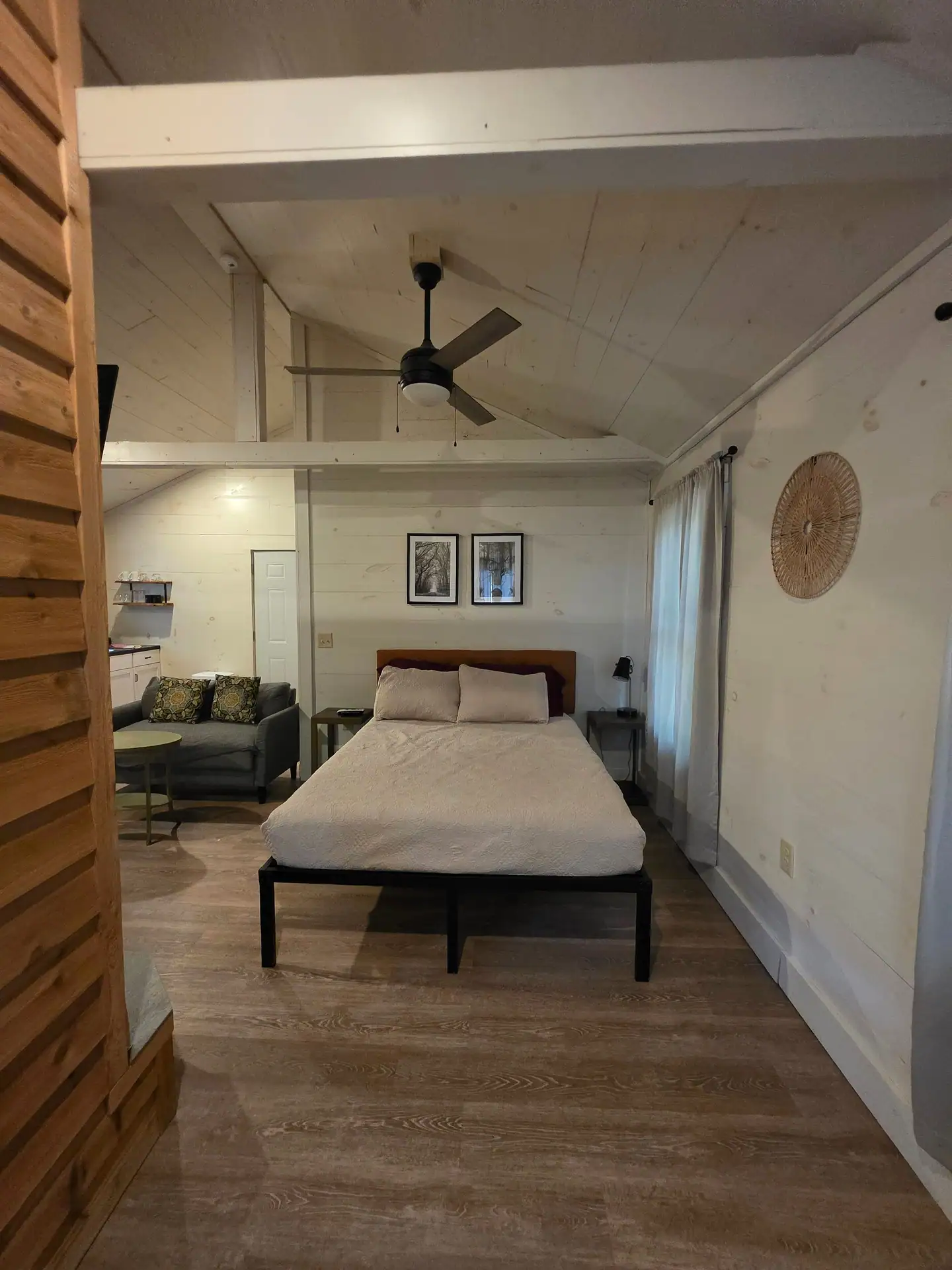 Sleeping area with queen bed and ceiling fan seen past the fireplace at Hummingbird cabin