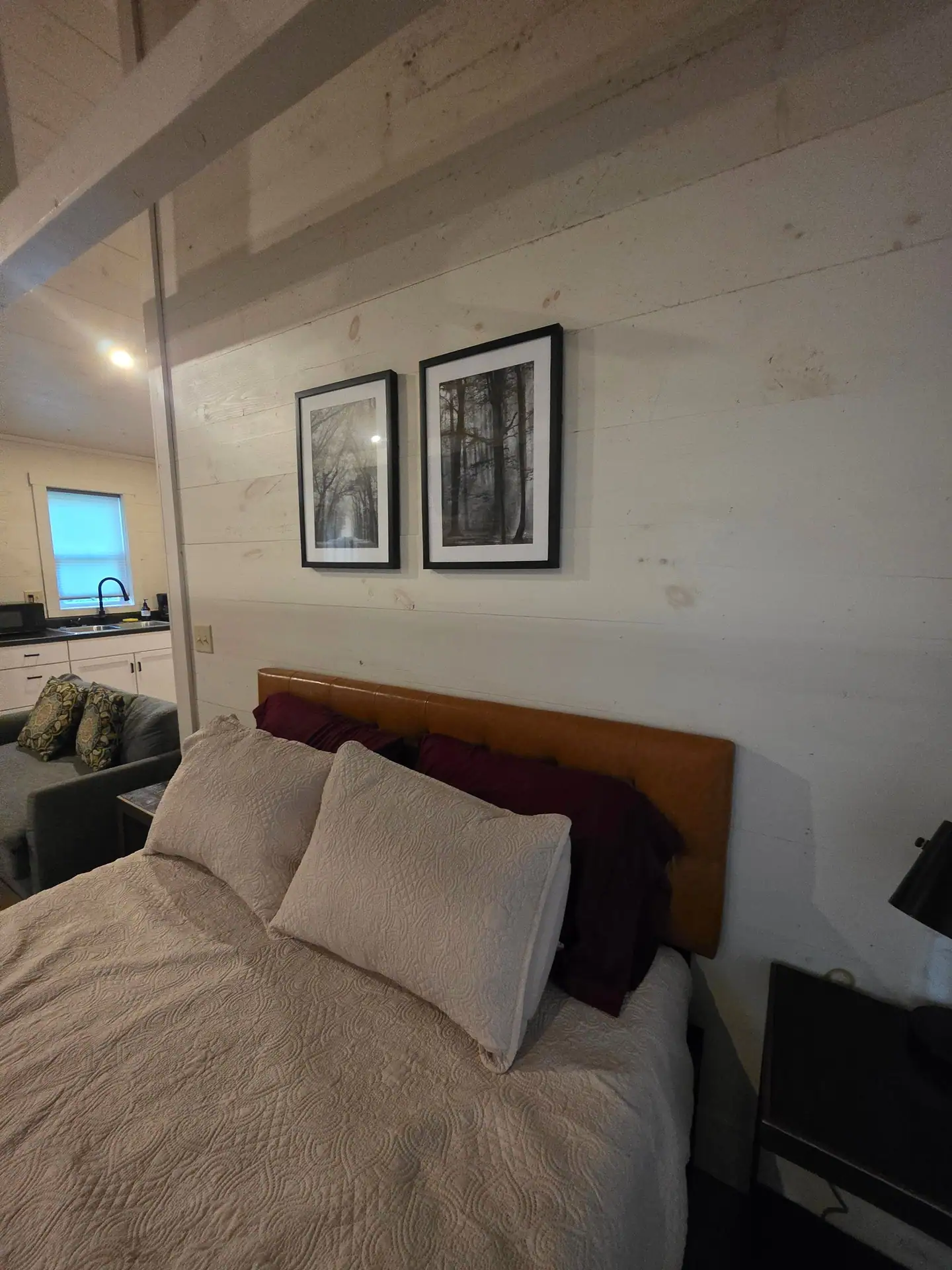 Queen bed with pillows, wooden headboard and framed tree prints at Hummingbird cabin