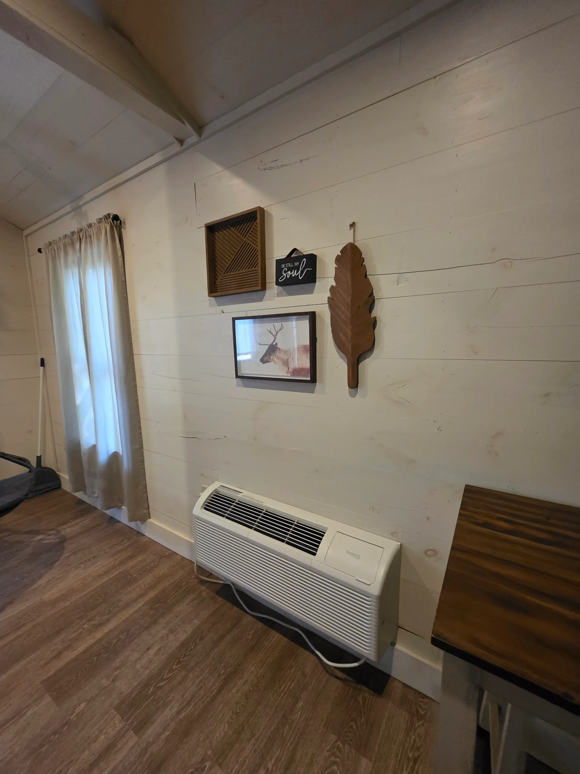 Wooden feather wall art, framed prints, and wall heater on shiplap at Hummingbird cabin