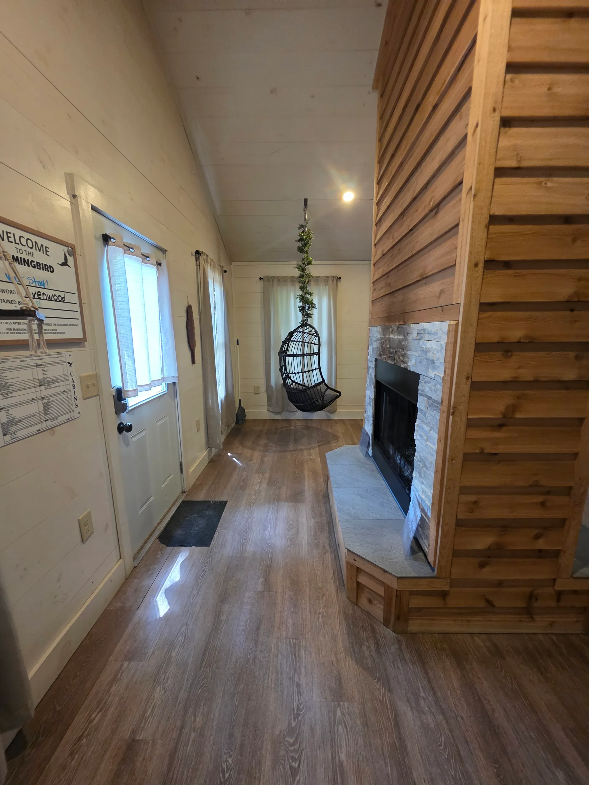 Interior entry view showing the cedar fireplace, hanging chair, and vaulted ceiling at Hummingbird cabin