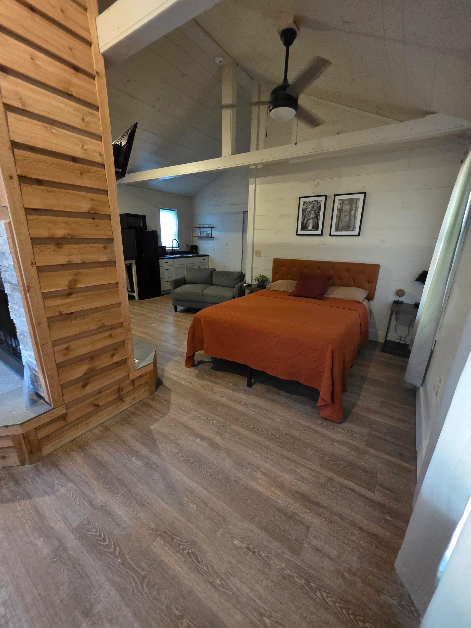 Open-concept interior with queen bed, cedar fireplace, and living area at Hummingbird cabin