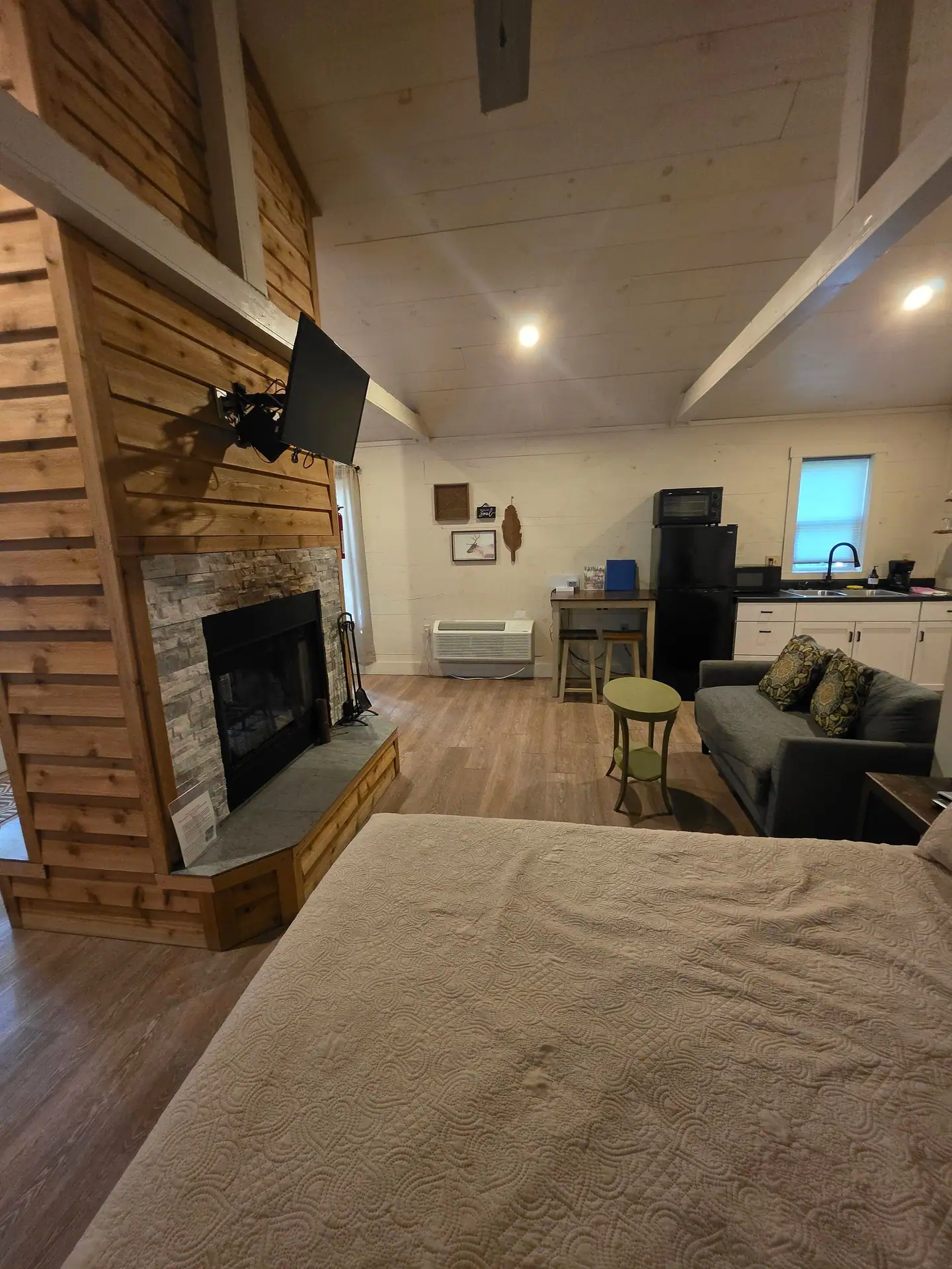 View from the queen bed toward the fireplace, sofa and kitchenette at Hummingbird cabin