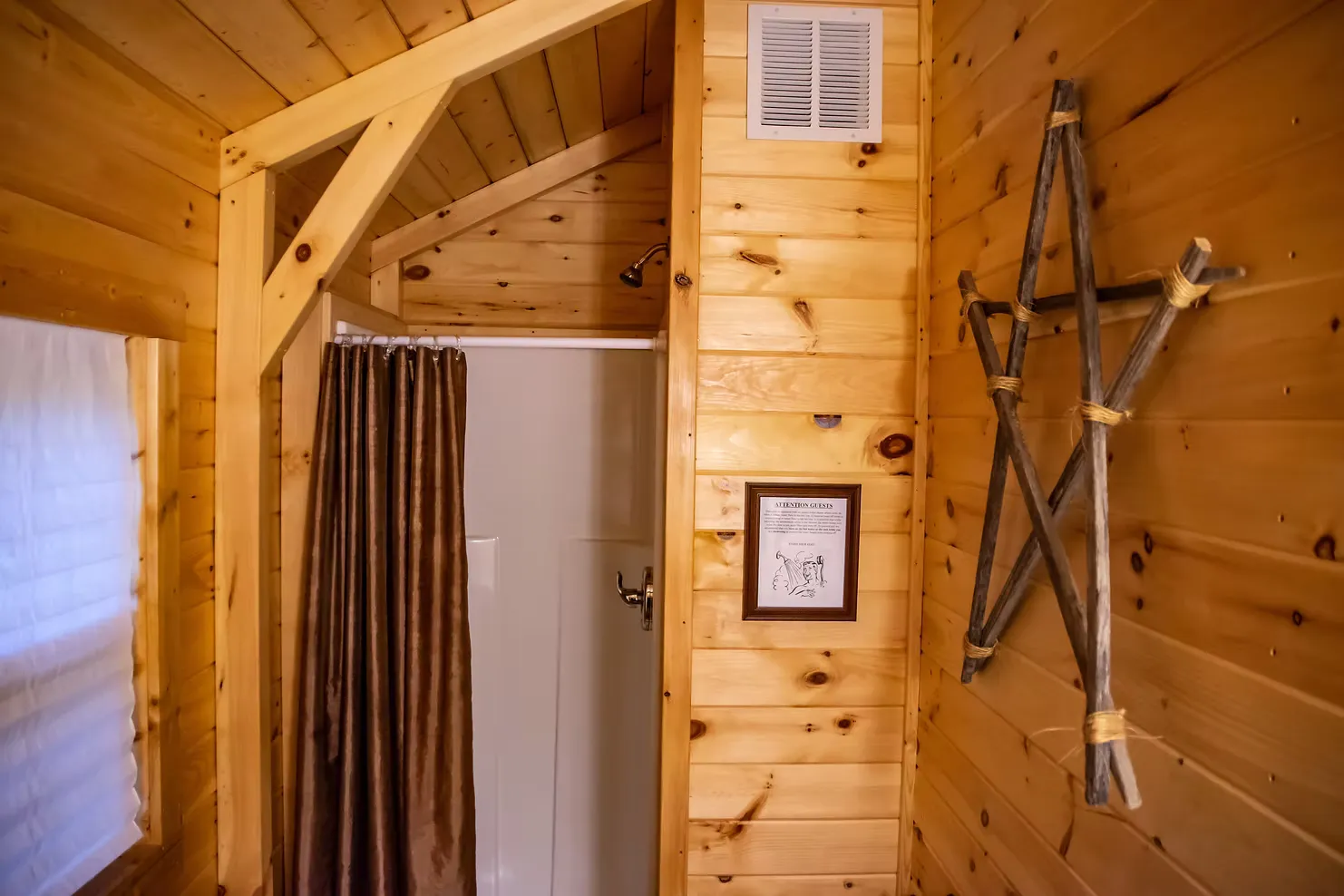 Bathroom with walk-in shower, curtain, and rustic twig star wall decor at Millers Den cabin
