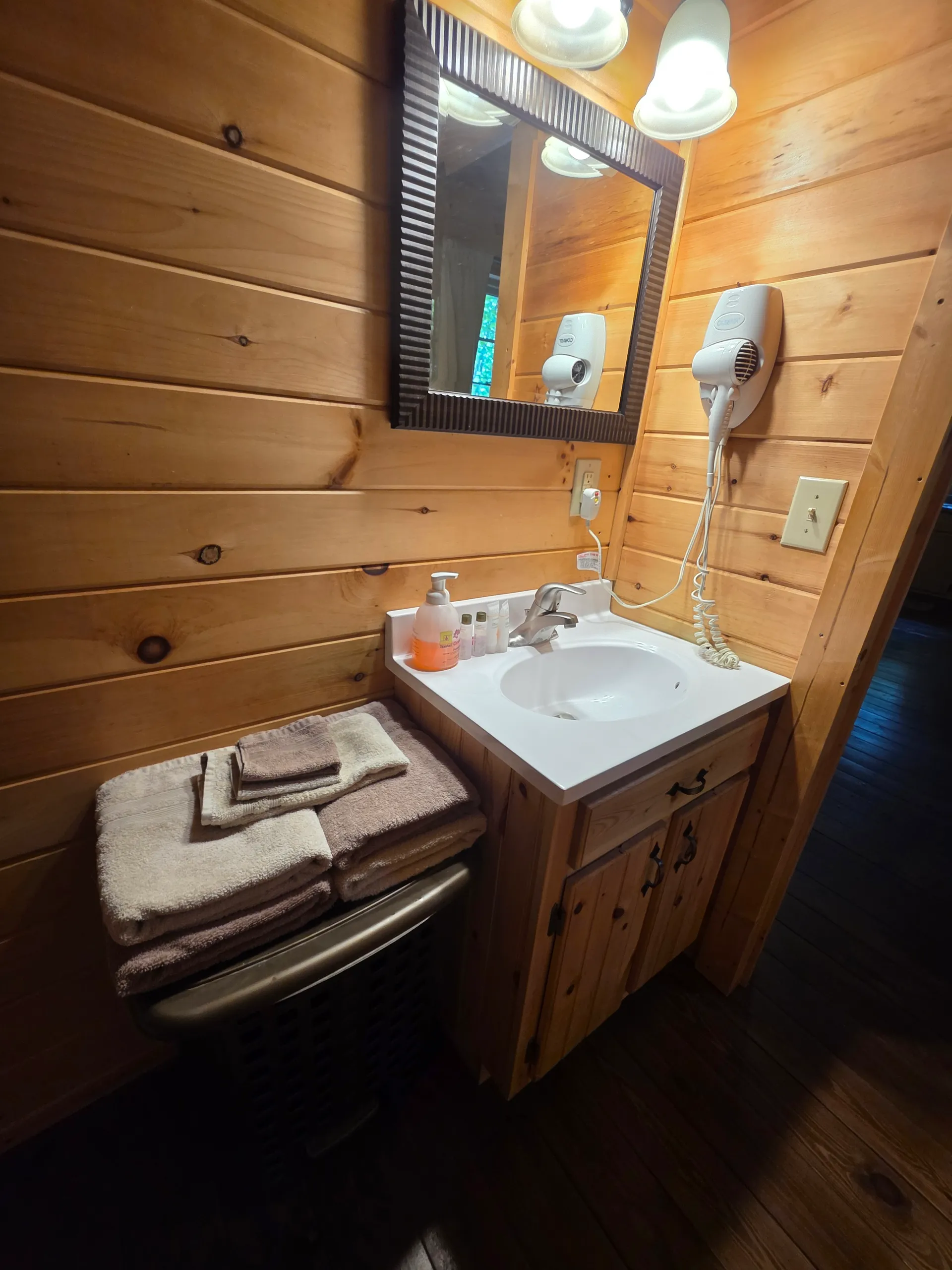 Bathroom vanity with mirror, hair dryer, and fresh towels at Millers Den cabin