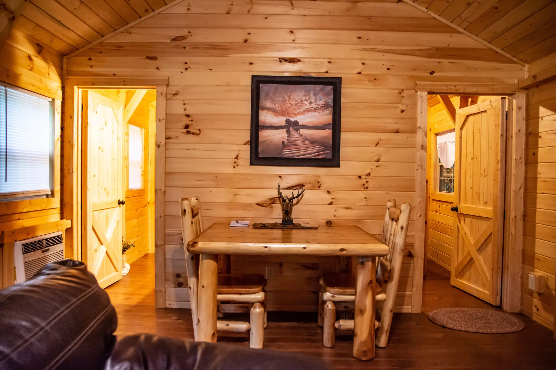 Rustic log dining table with chairs and wall artwork at Millers Den cabin