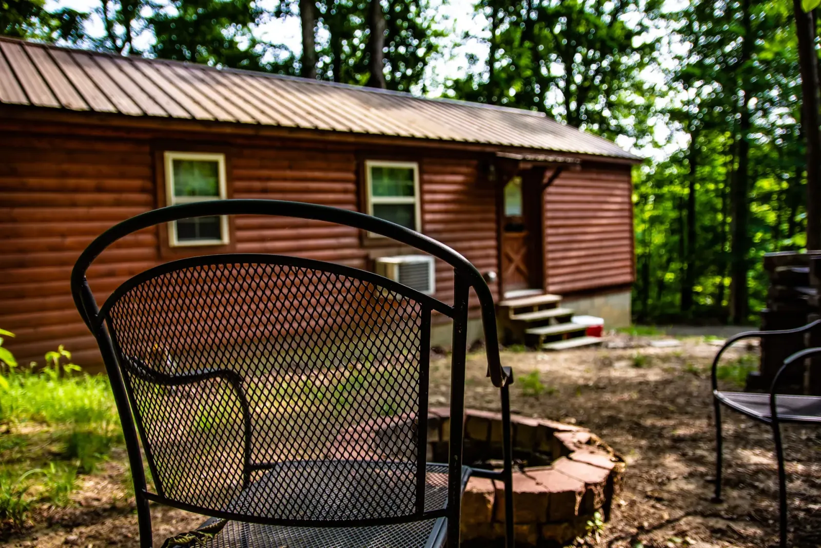 Front exterior of Millers Den cabin with fire pit and metal seating chairs