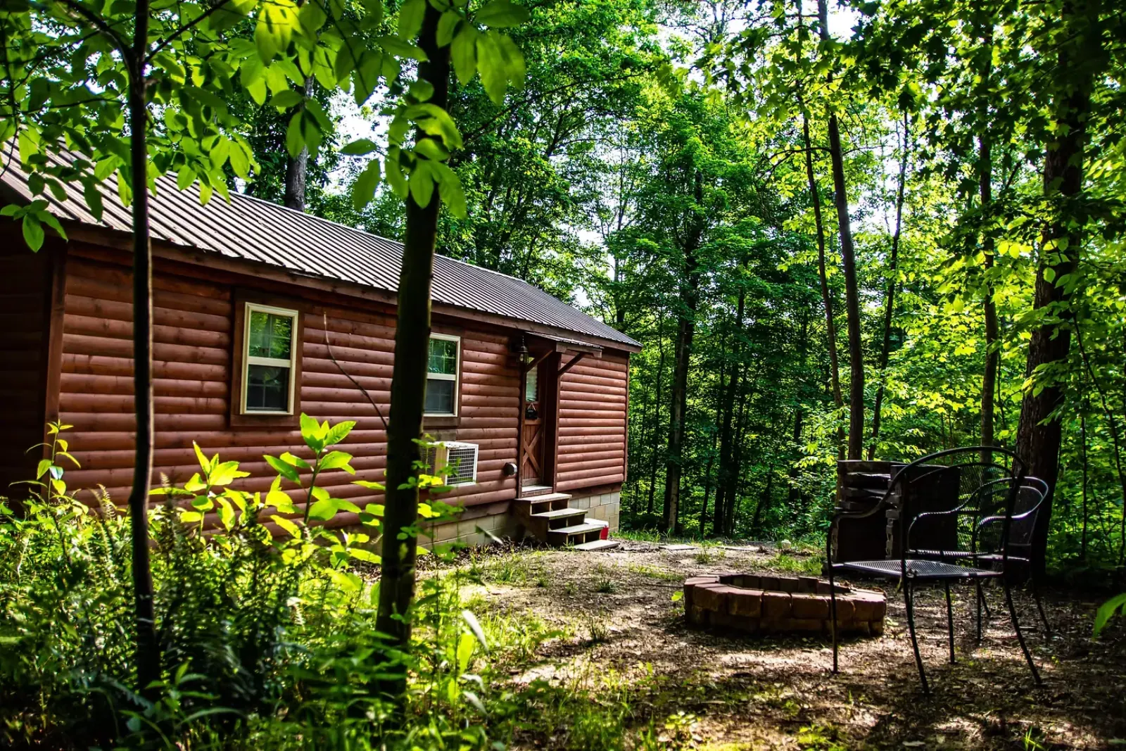 Side exterior view of Millers Den log cabin with fire pit and metal chairs in Hocking Hills