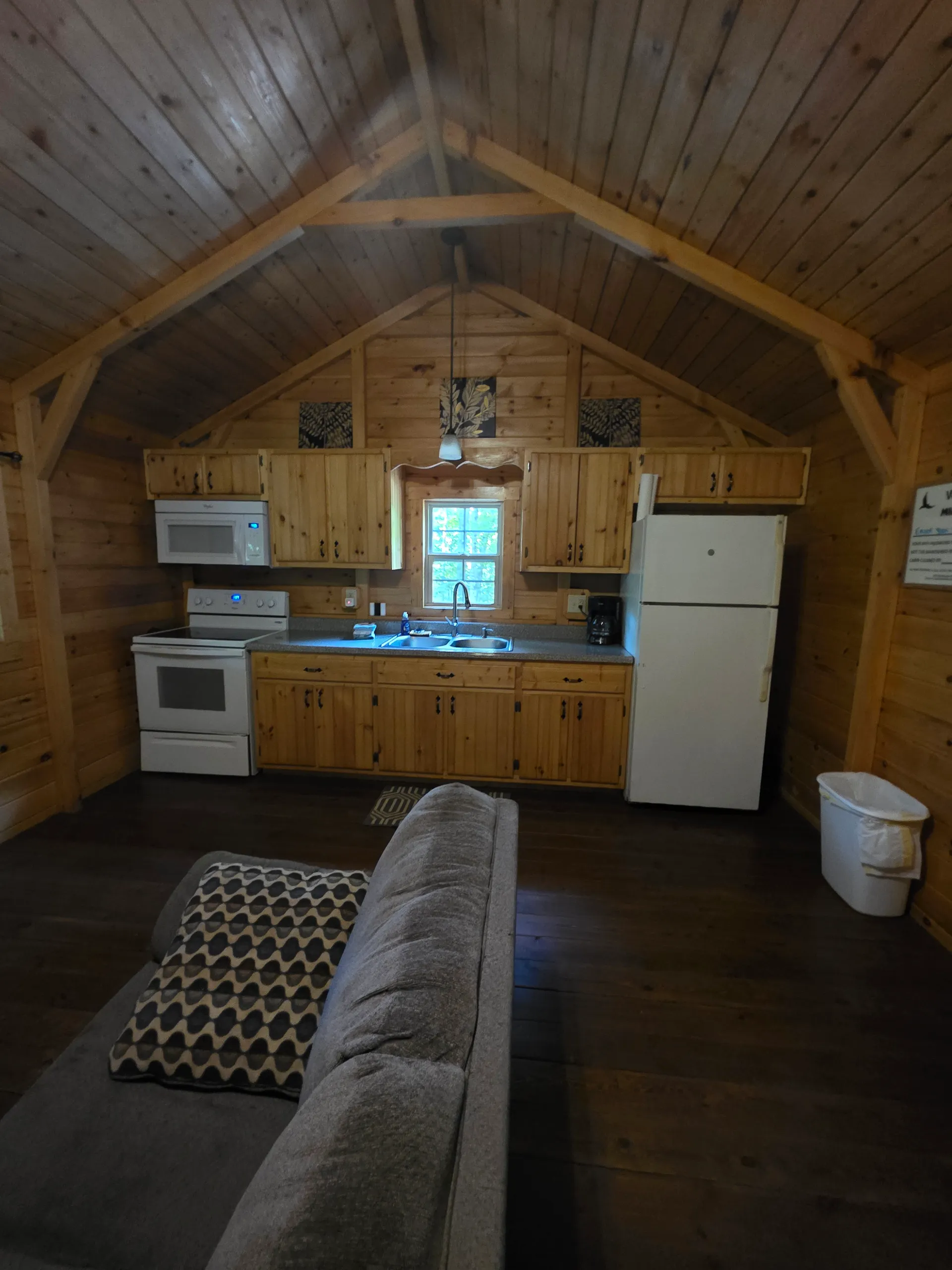 Fully equipped kitchen with pine cabinets, refrigerator, and microwave at Millers Den cabin