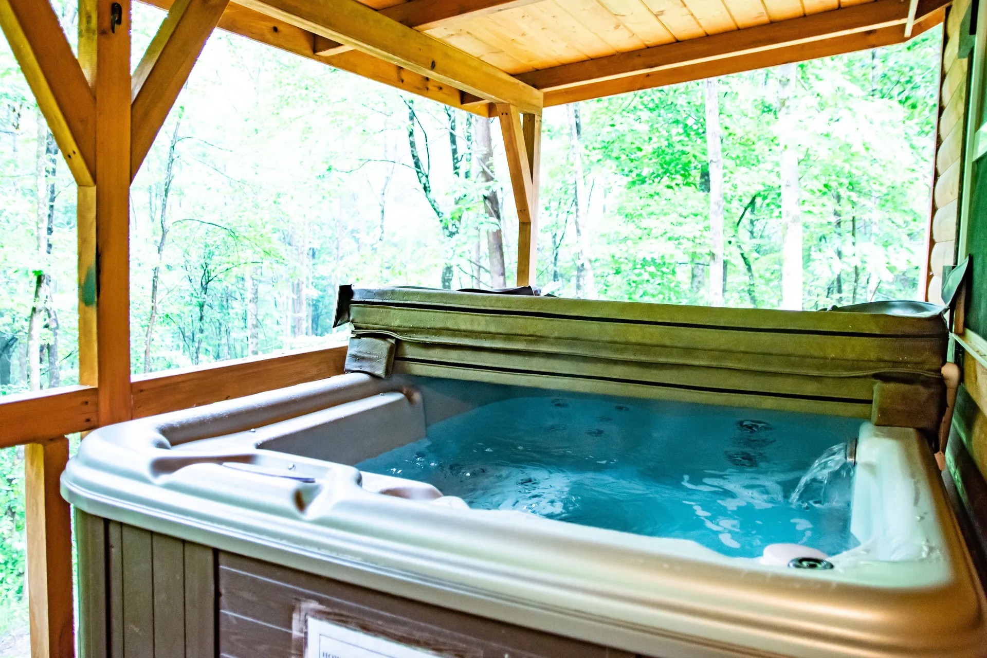 Private hot tub on covered deck with forest views at Millers Den cabin