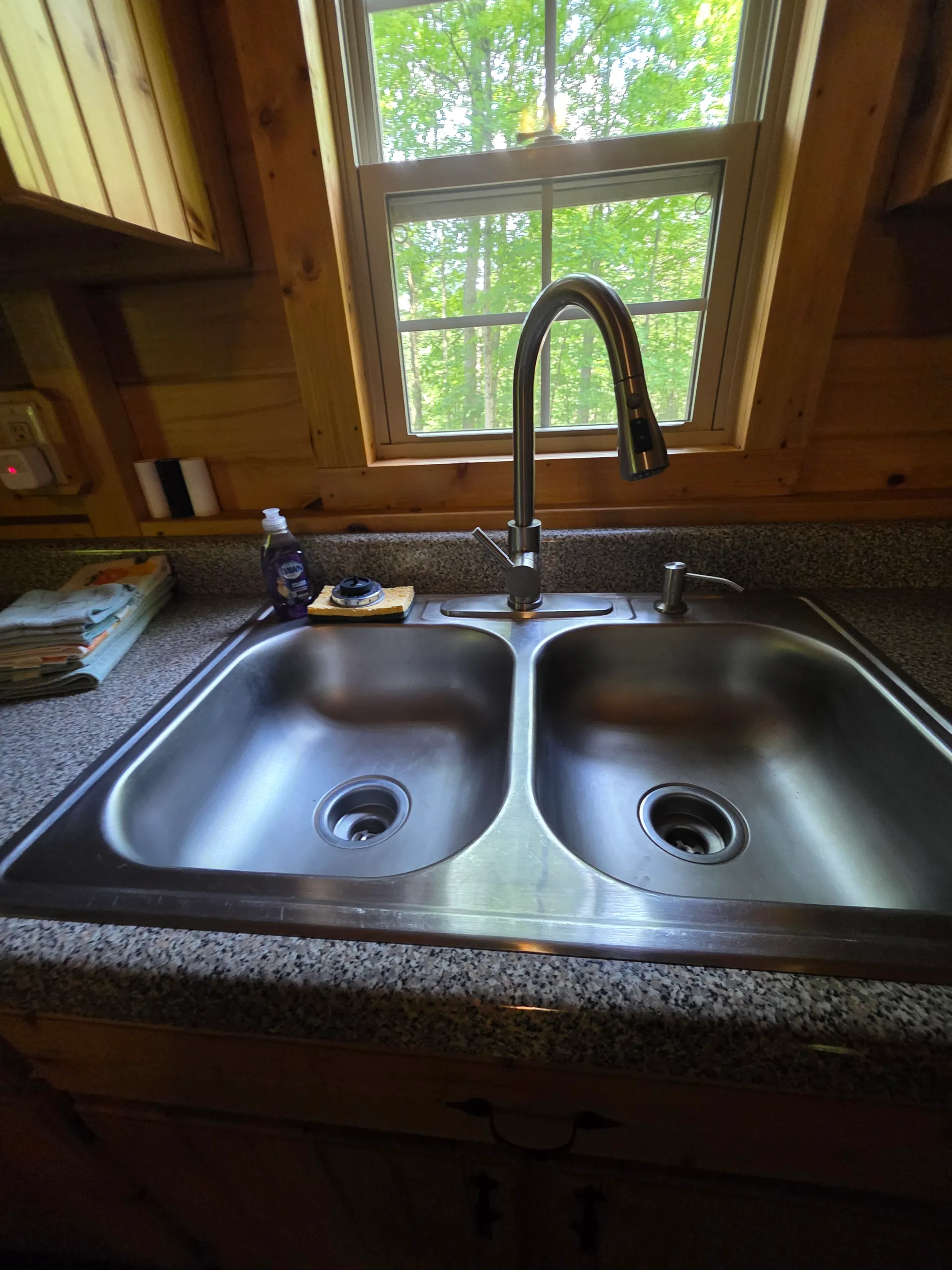 Double basin kitchen sink with forest window view at Millers Den cabin