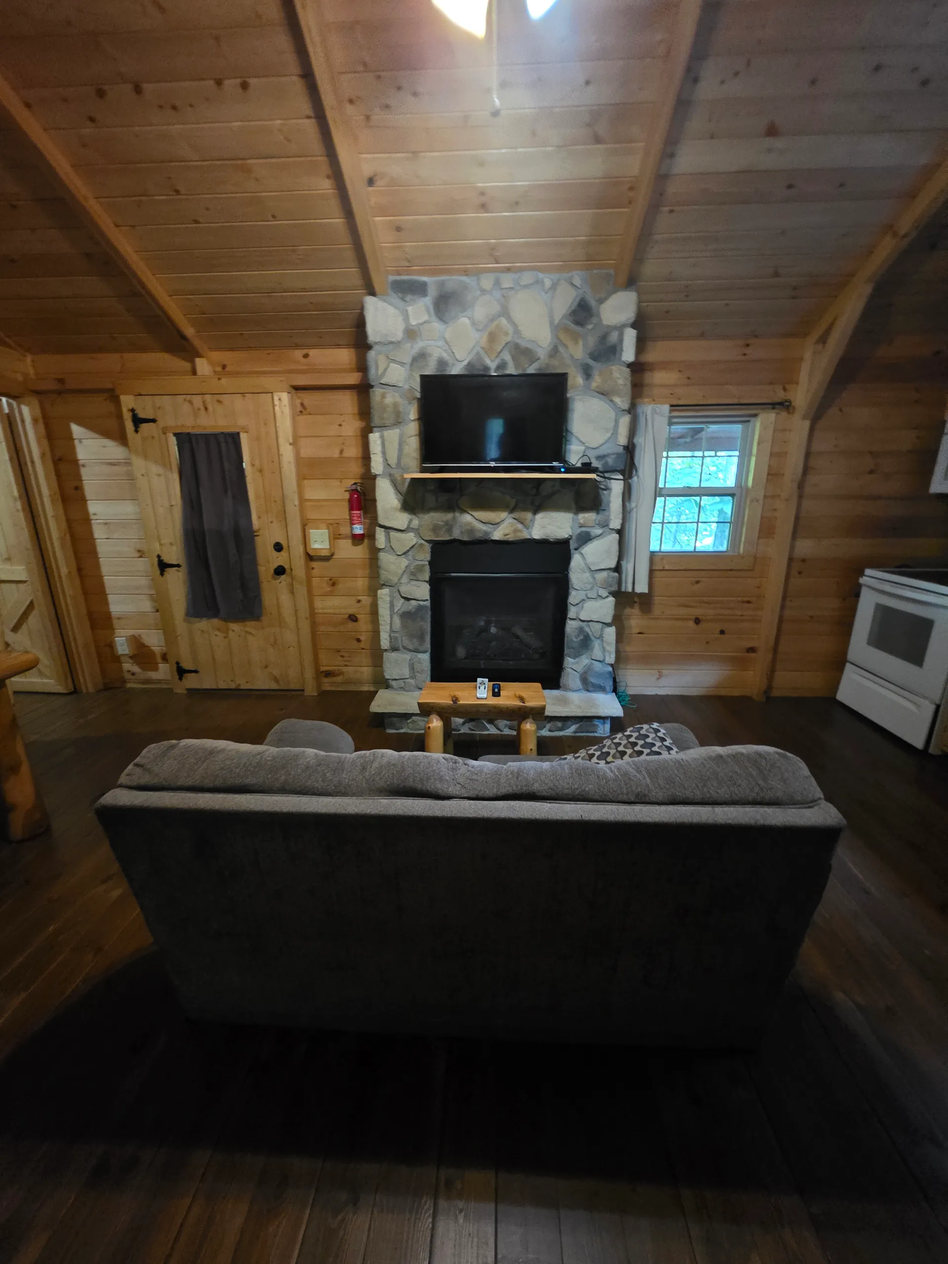 Living room with stone fireplace, flat-screen TV, and cozy sofa at Millers Den cabin