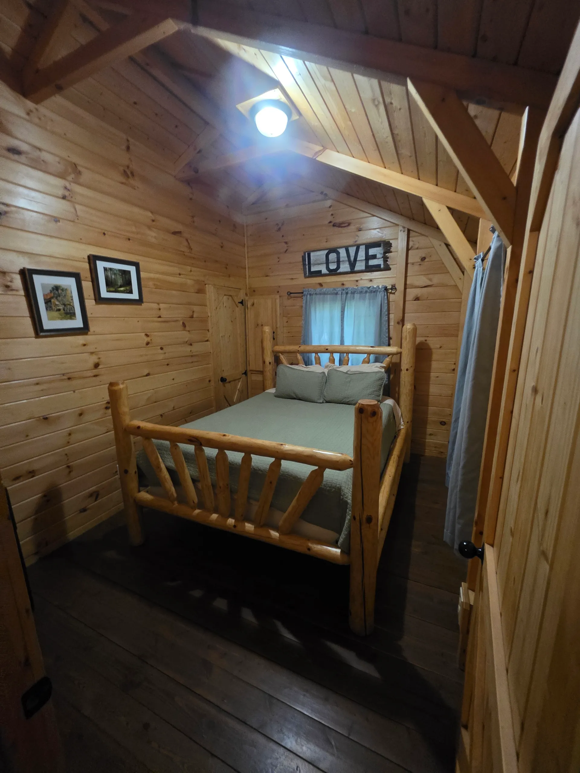 Cozy loft bedroom with rustic log bed frame and pine walls at Millers Den cabin