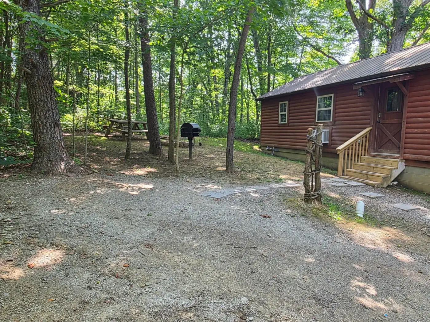 Side yard and charcoal grill area at Millers Den cabin surrounded by trees