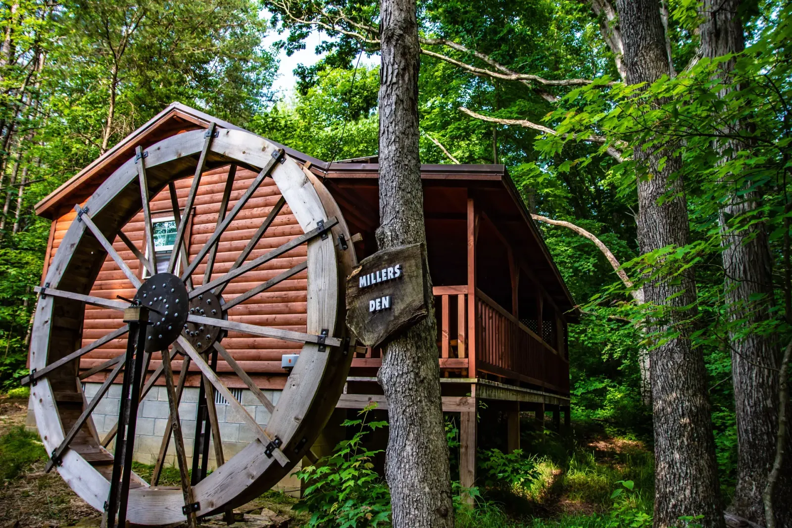 Millers Den cabin entrance with decorative water wheel and wooden name sign