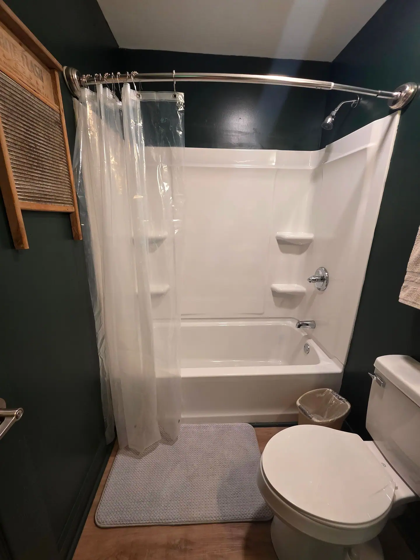 Bathroom with tub and shower combination and vintage washboard on the wall at The Old Moonshiner cabin