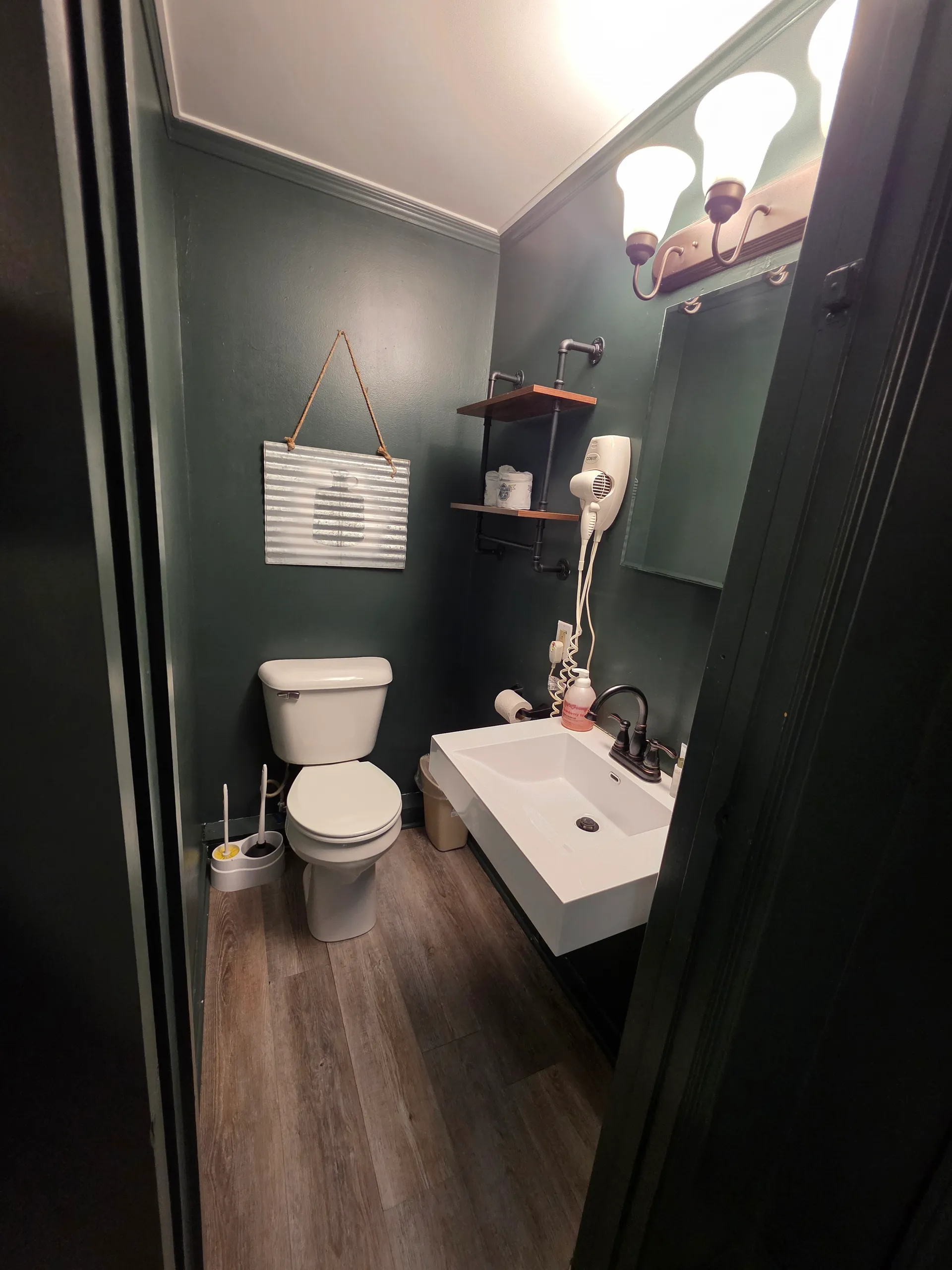 Modern bathroom with vessel sink, dark green walls, and vanity lighting at Moonshiner cabin