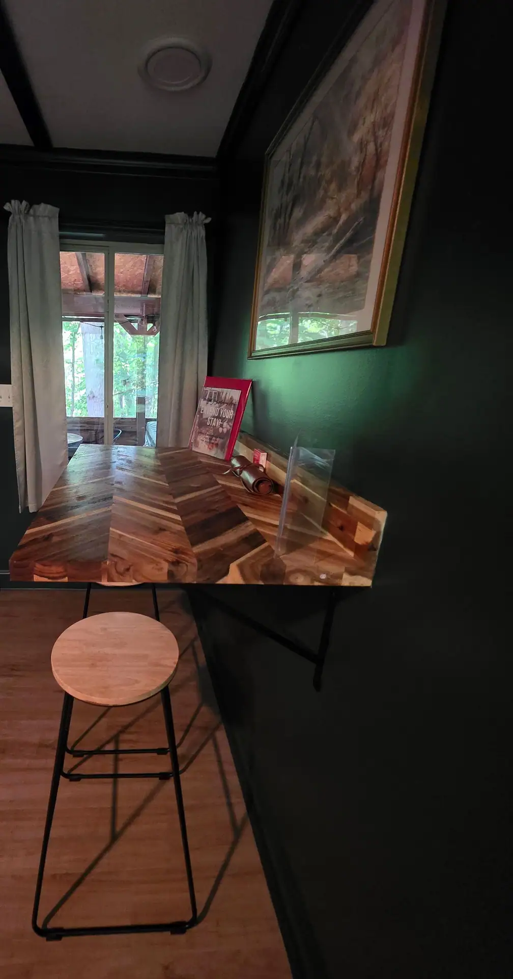 Wood breakfast bar with a stool next to a window onto the screened porch at The Old Moonshiner cabin