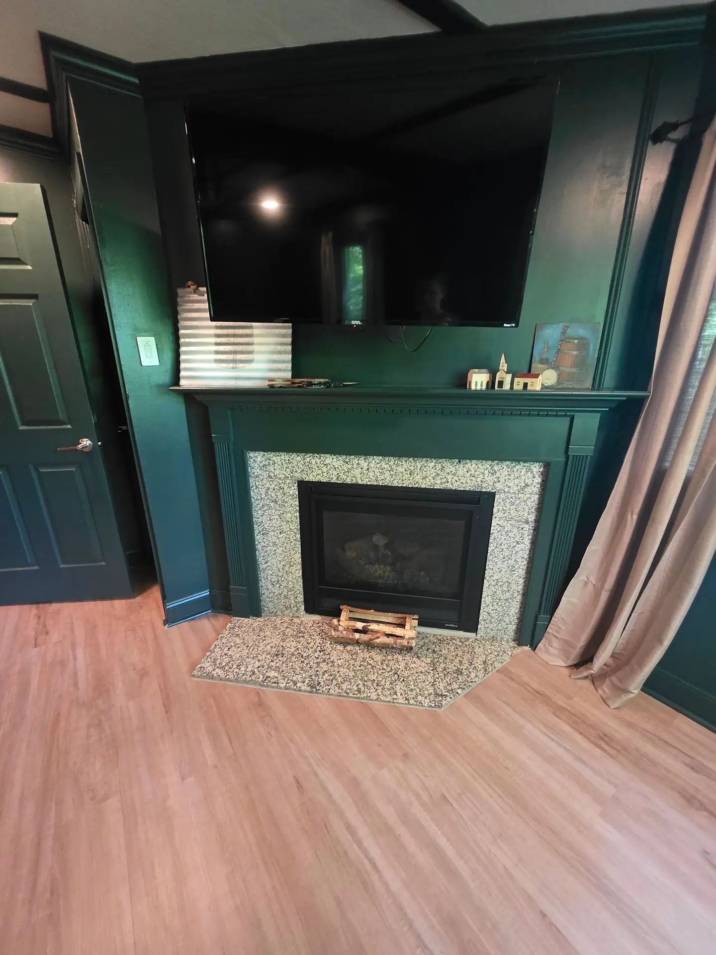 Gas fireplace with granite surround and hearth below a wall-mounted TV at The Old Moonshiner cabin