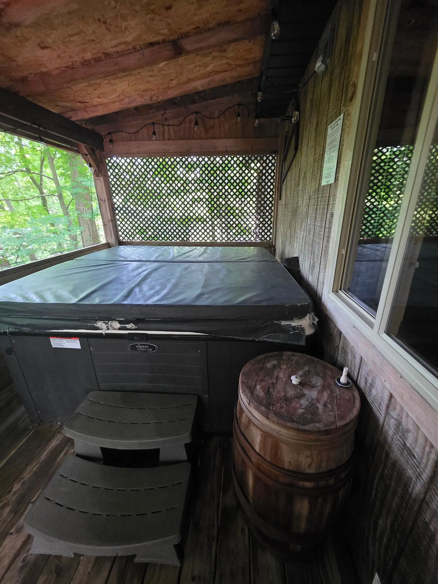 Hot tub with steps and whiskey barrel on the screened porch at The Old Moonshiner cabin