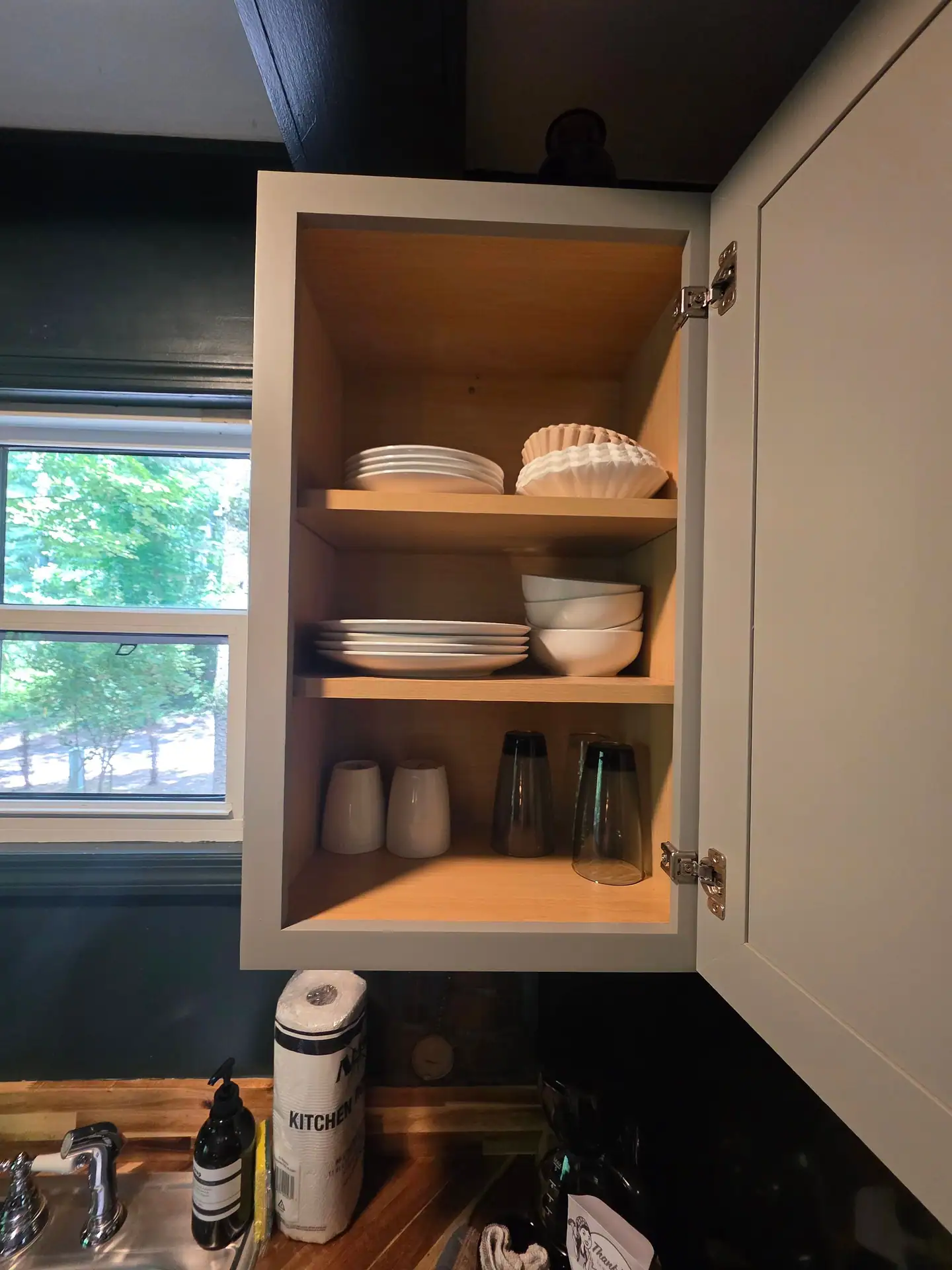 Open kitchen cabinet with plates, bowls and glasses at The Old Moonshiner cabin