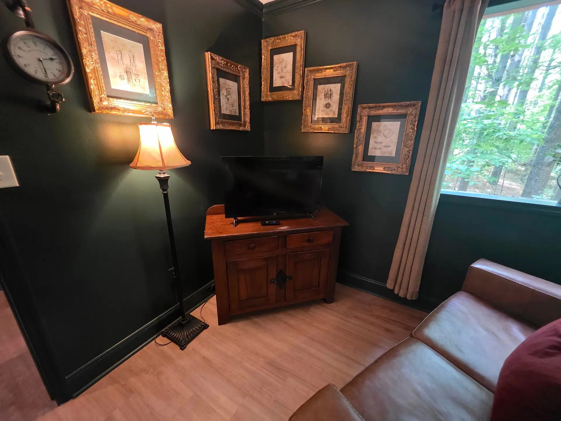 TV on a wooden cabinet below gold-framed moonshine still prints at The Old Moonshiner cabin