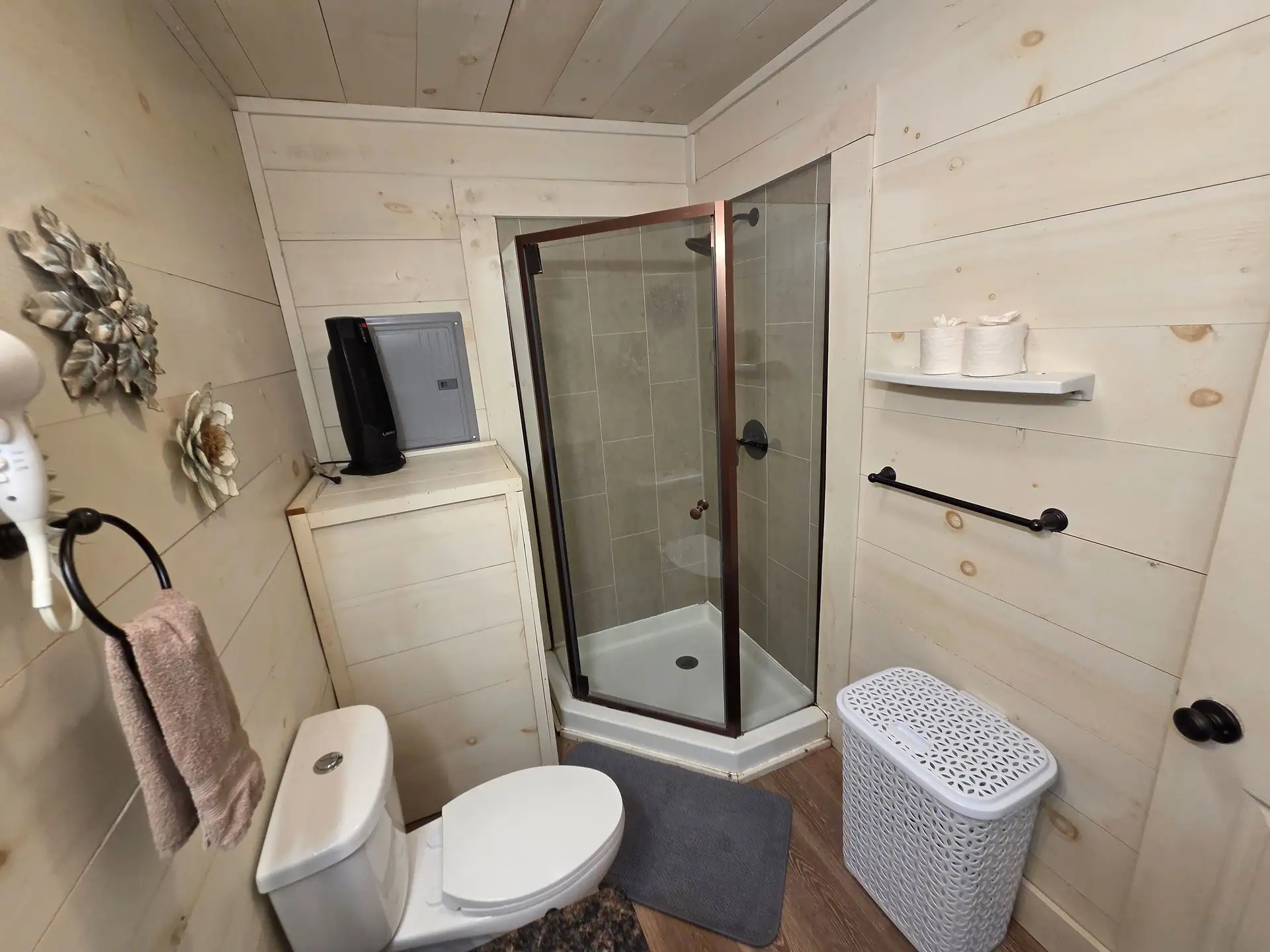 Glass-enclosed corner shower with decorative metal art on the shiplap wall at Owl's Tale cabin