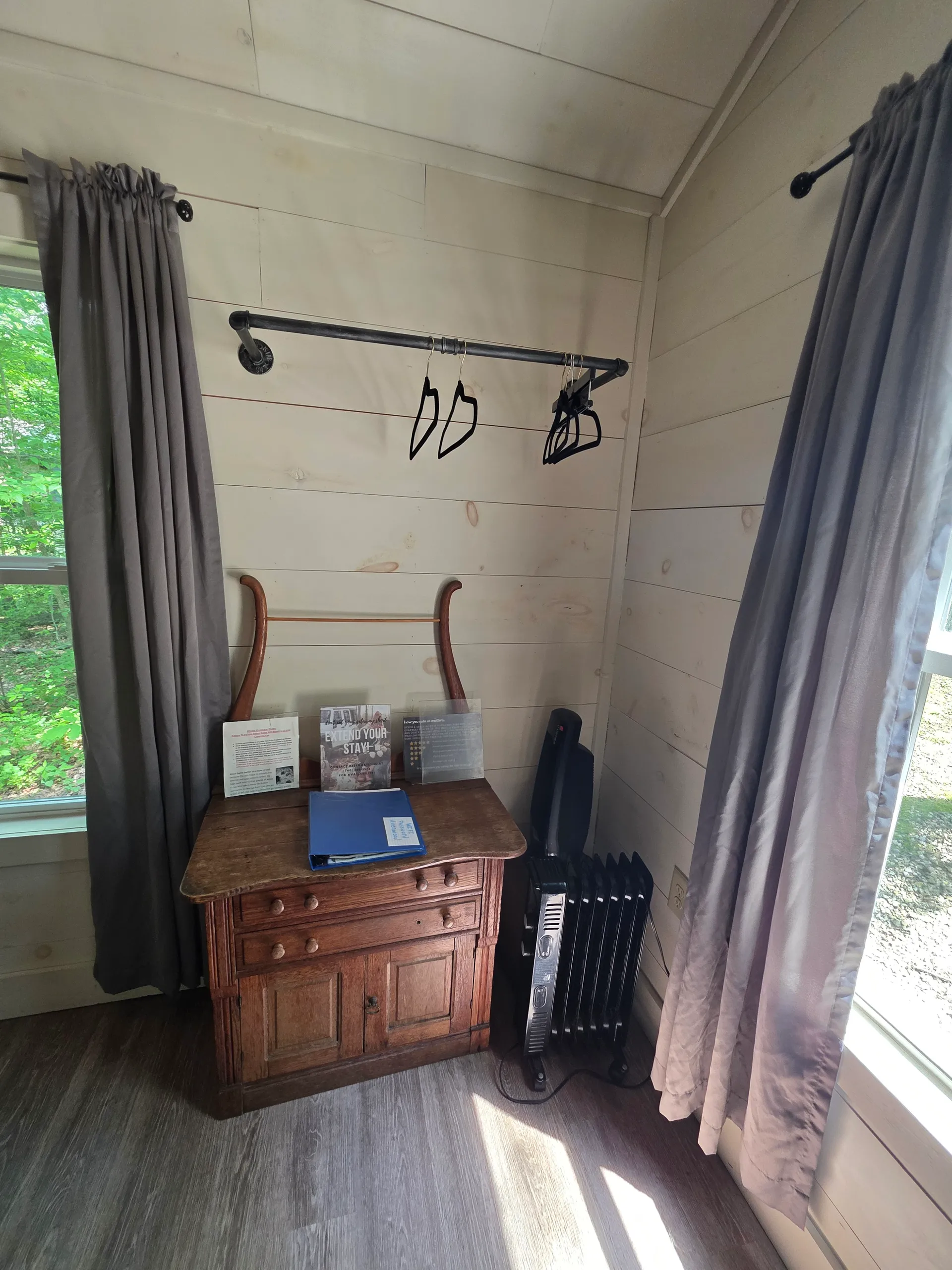 Bedside area with wooden nightstand, clothing rack, and heater at Owl's Tale cabin
