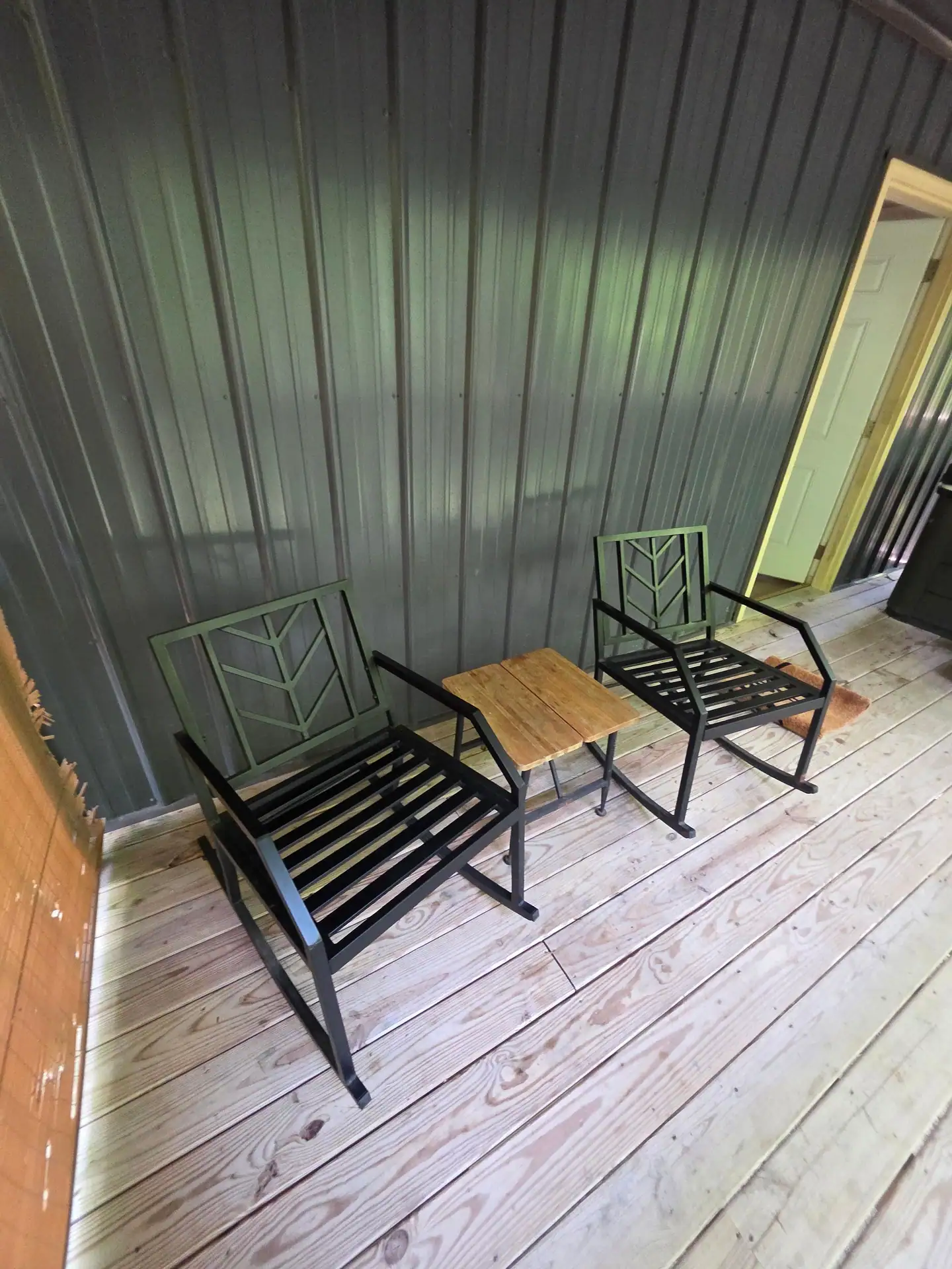 Two metal chairs and a small wood table on the covered deck at Owl's Tale cabin